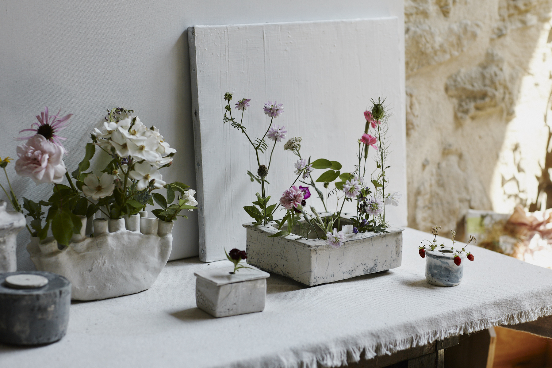 Various vases made by Cécile complete with flowers.