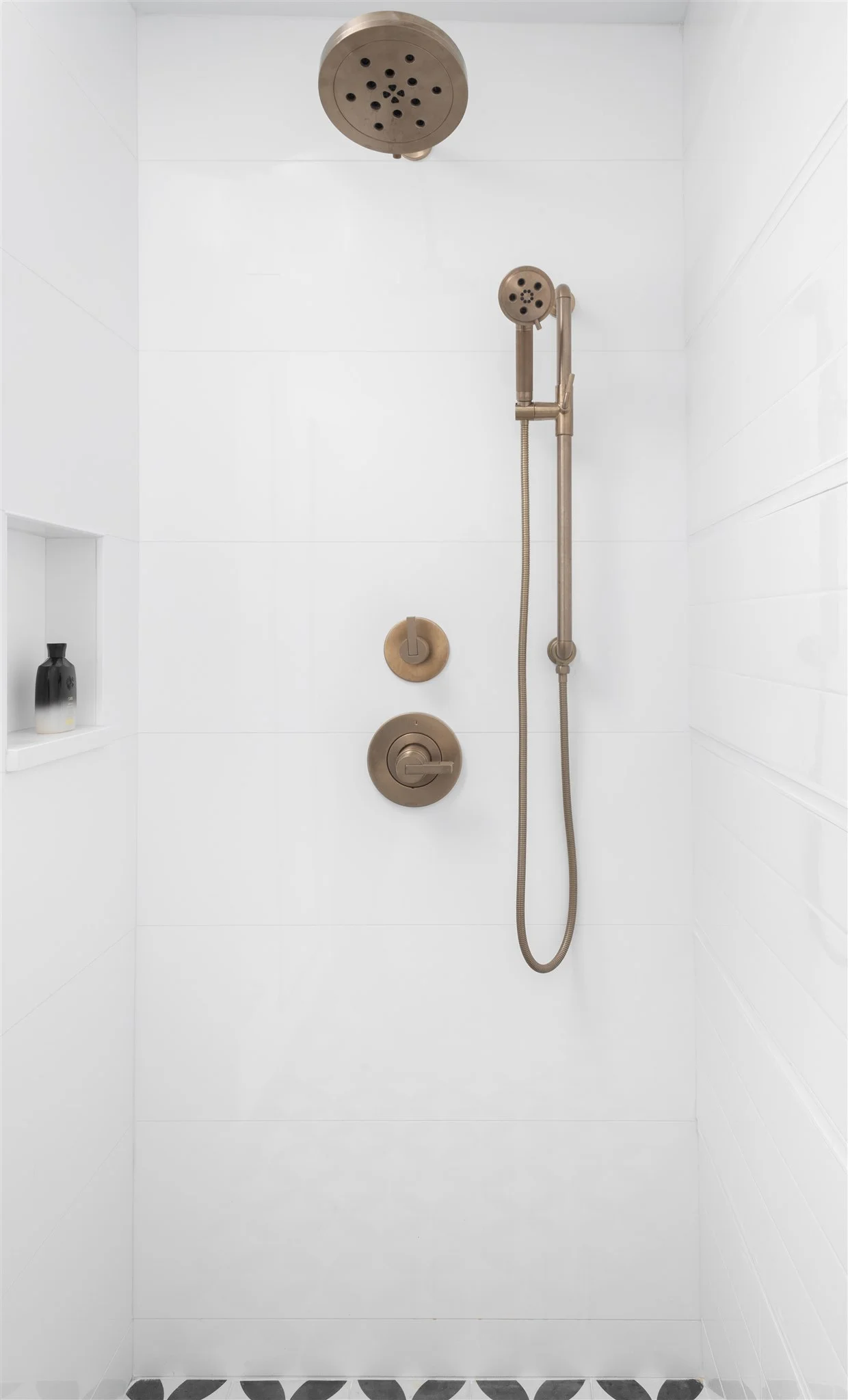 In the shower, we carried in large format white tiles towards the front and back and then played with the pattern of the long subway tiles on the side wall so that all of the horizontal grout lines aligned with the larger format tiles.