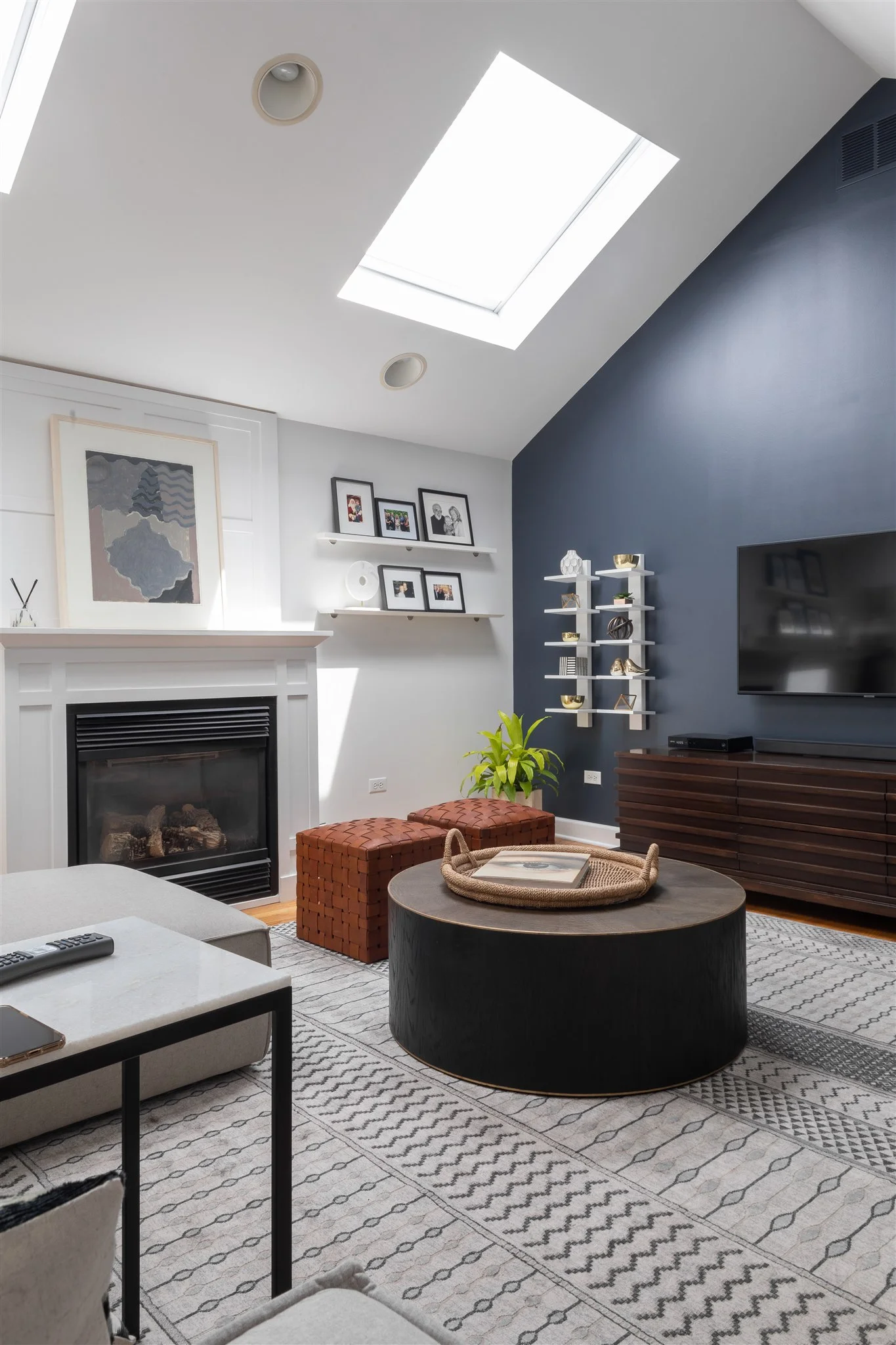 This family room is perfect for both sunny days and rainy mornings. We introduced two sectionals to round out the space and create the perfect areas to curl up in front of the fire or TV. Beside the TV, we carried in the same shelves I installed in the clients last home to add some texture and styled them with some brass accessories to tie everything together.