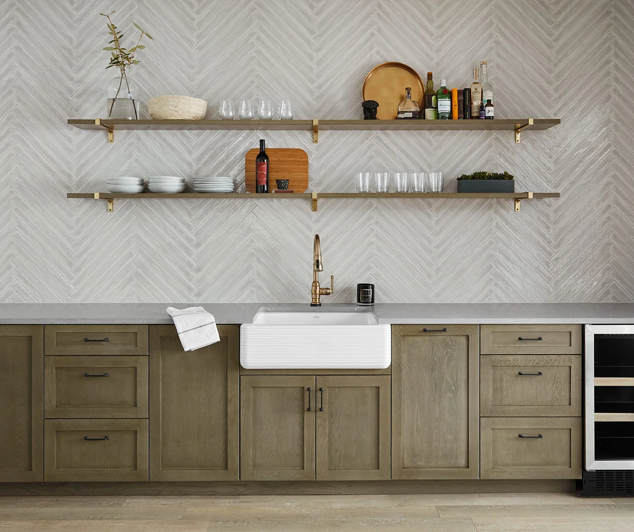 At the kitchenette, we incorporated the same wall tile from the bathroom to keep things cohesive, but installed it in a herringbone pattern to elevate it a bit. Storage, trash and appliances are strategically incorporated and concealed along the bot…
