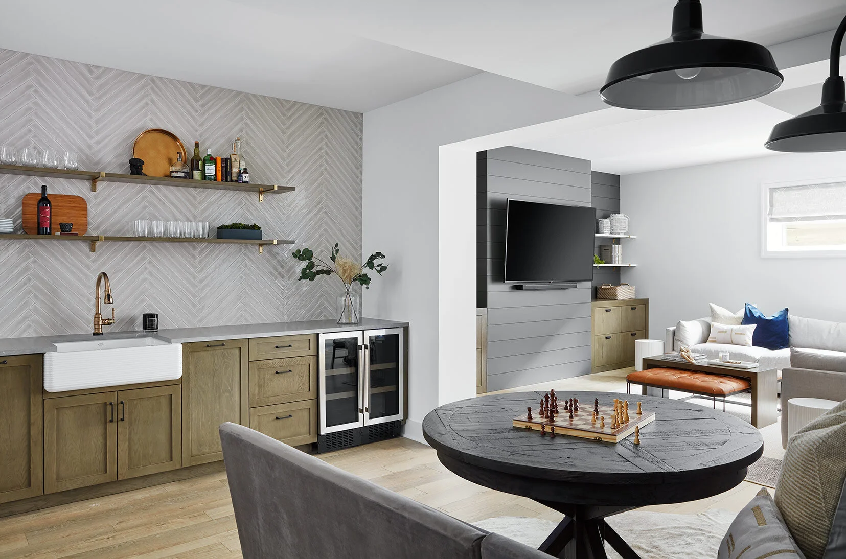 An L-shaped banquette with wall sconces and a round table provides space for friends and family to enjoy games and conversation while still feeling open and connected to the kids and family area.