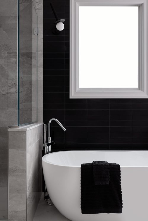 White bathtub contrasted against black tiles.