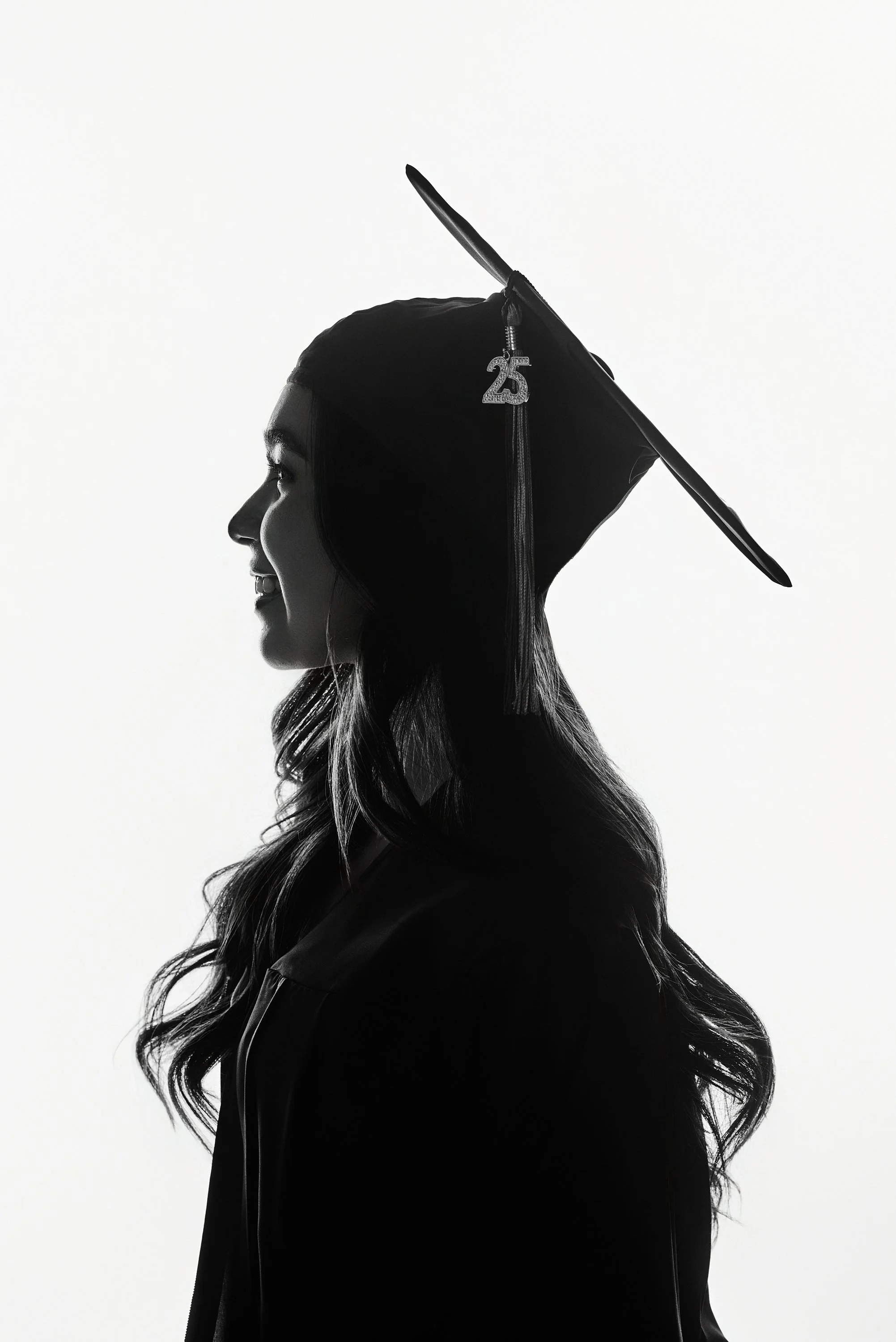 Perfil de una mujer con toga y birrete de graduación, en blanco y negro, con un fondo blanco.