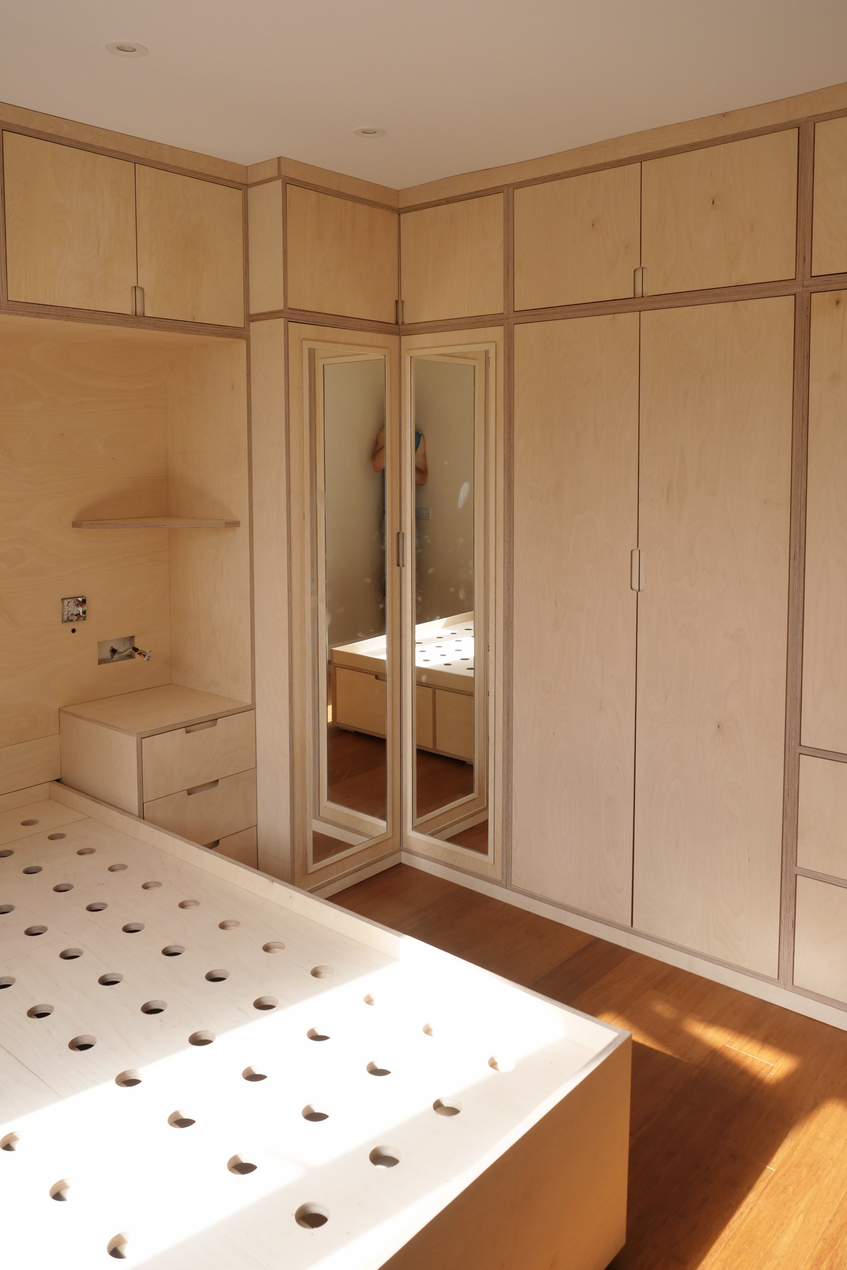 birch plywood ply bedroom wardrobe showing a double corner mirror with corner cupboards, plywood edge grain and luxurious luxury contemporary fitted custom furniture by a local somerset craftsman cabinet maker in south west england near bath bristol