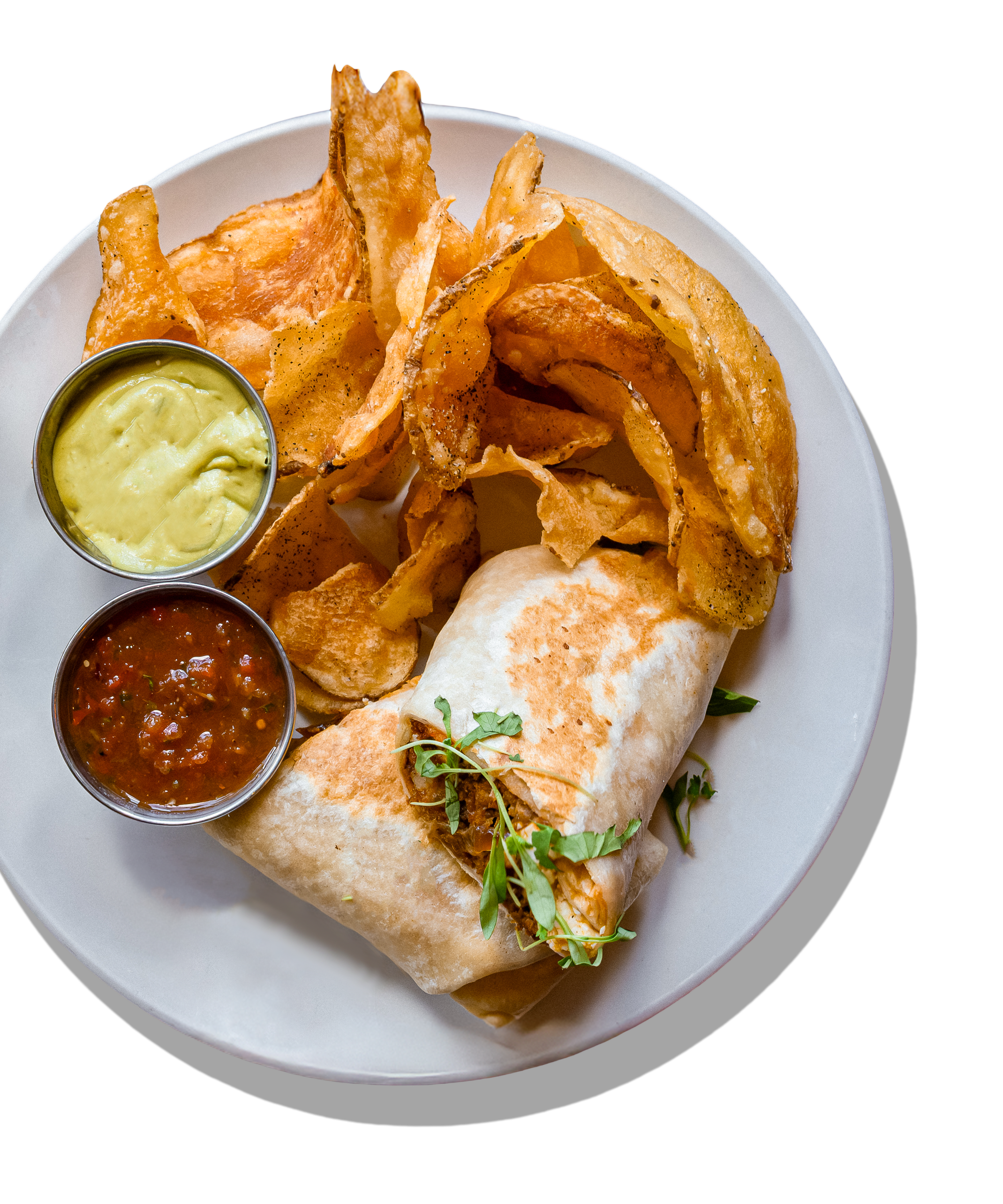 Plate of potato chips, two small bowls of guacamole and salsa, and a burrito garnished with herbs.