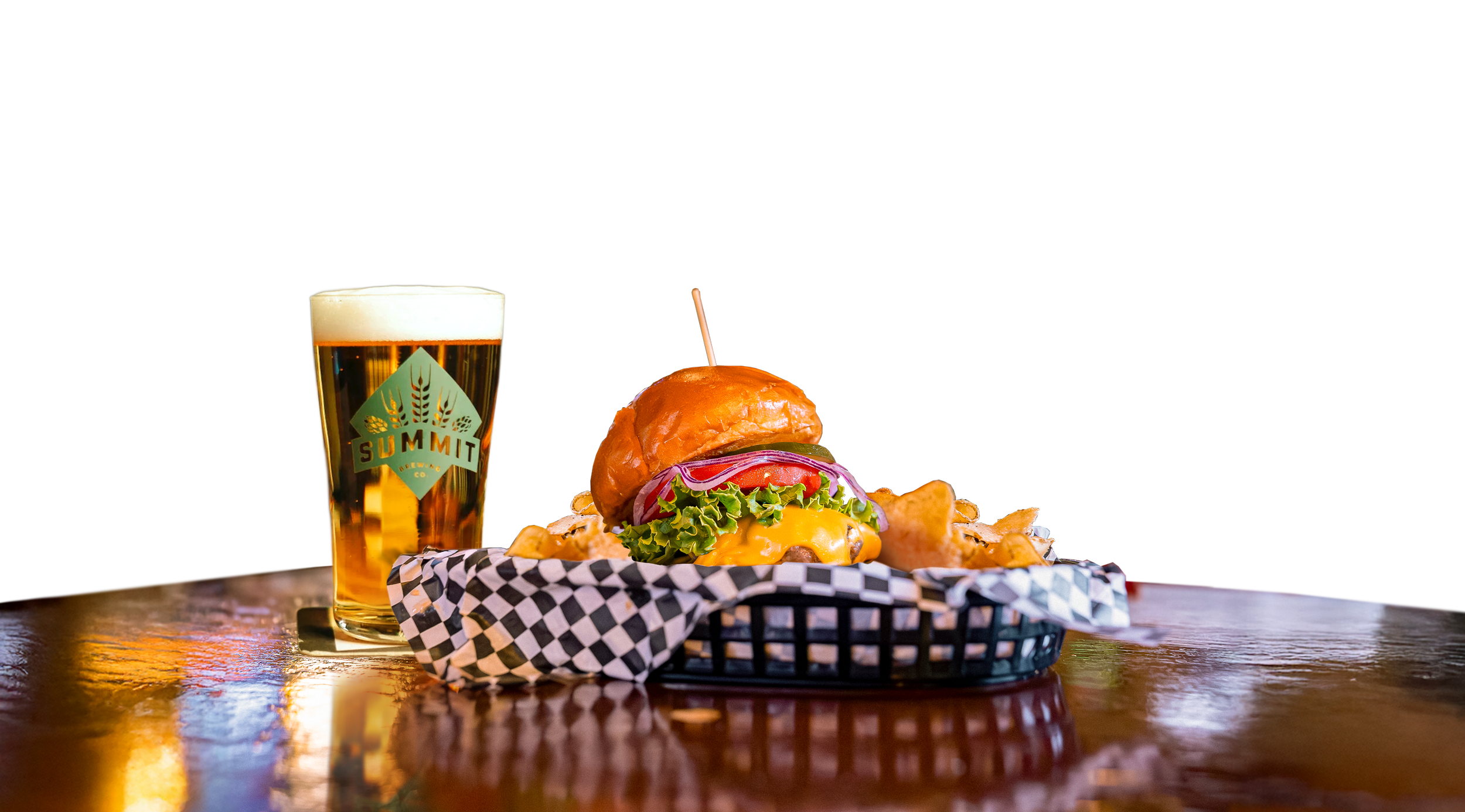 A cheeseburger with lettuce, tomato, red onion, pickles, and melted cheese in a bun, served with potato chips in a basket, alongside a pint of beer with a logo reading 'SUMMIT'