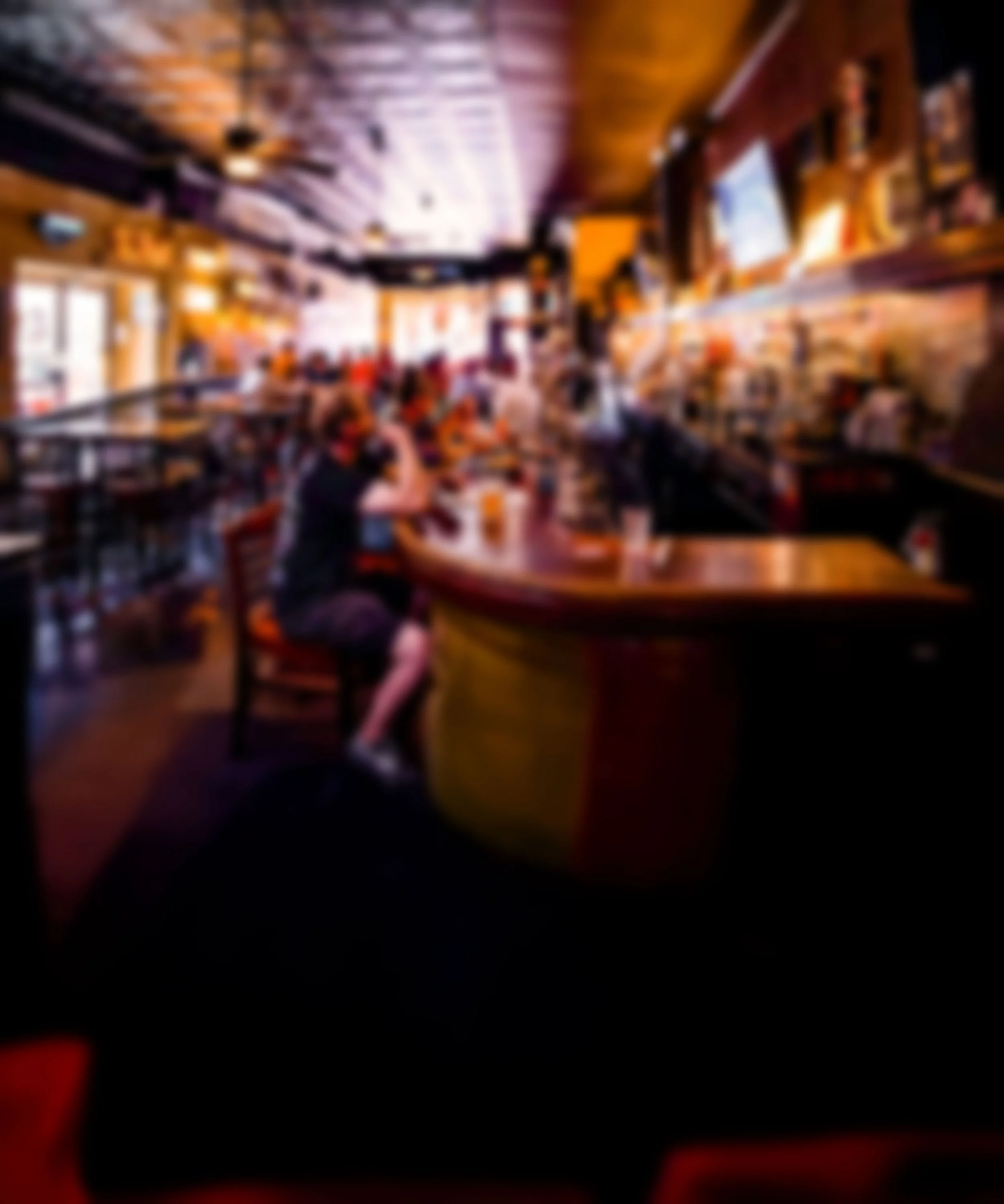 A group of people at a bar or restaurant with wooden decor, eating and drinking.