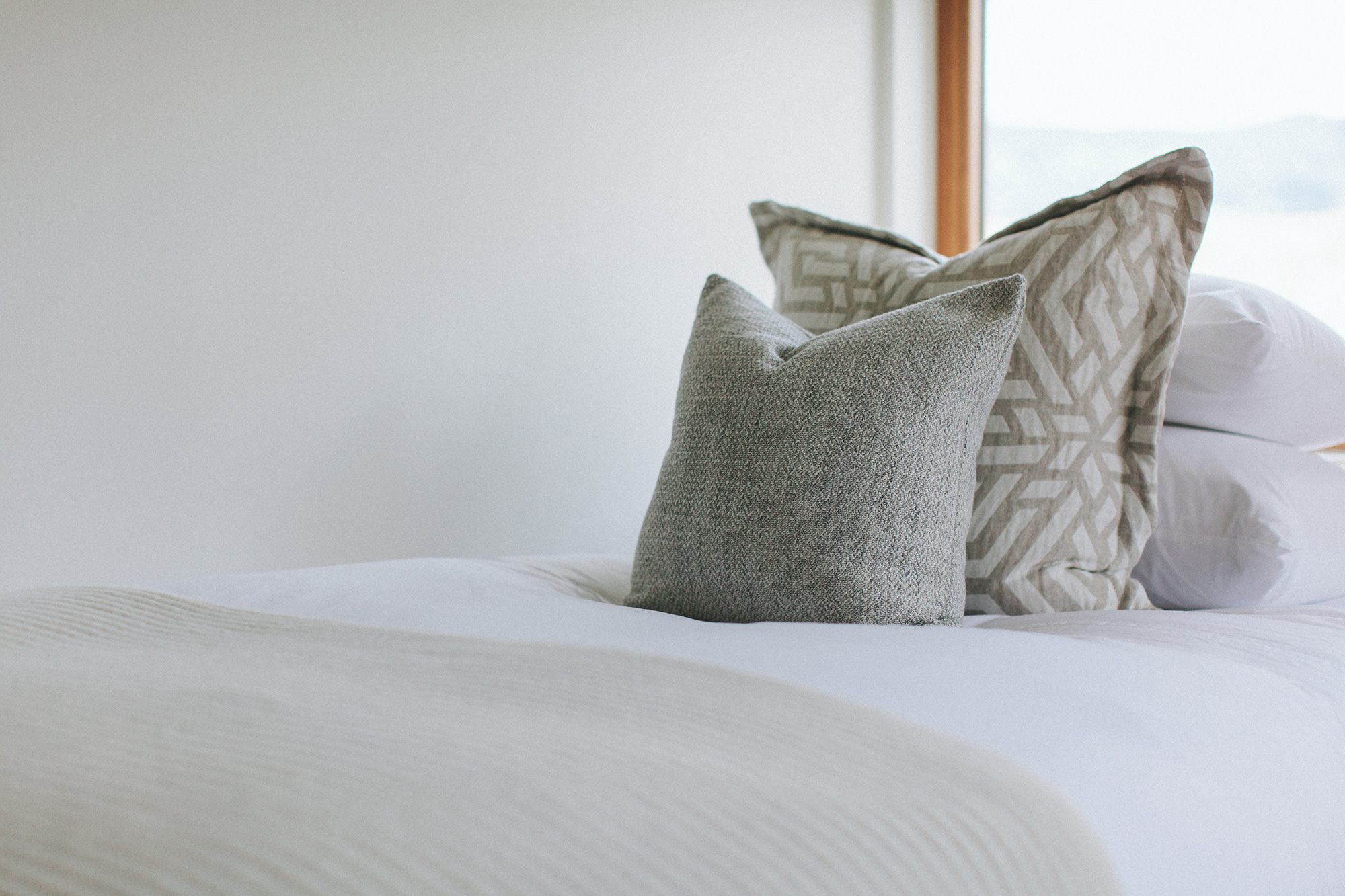  A modern white bed with two gray pillows  