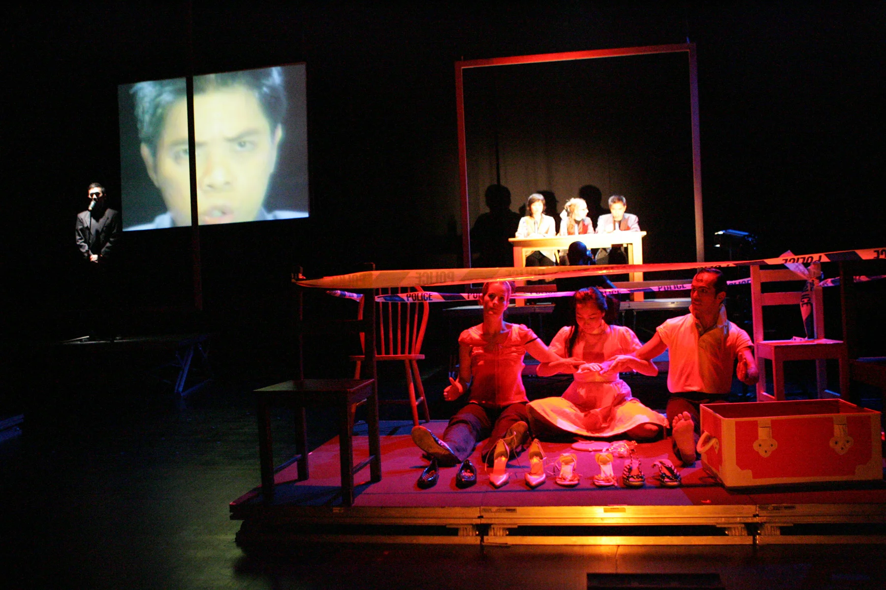 In the foreground during Scenario 11, Amy Ka Man Tam 'plays' Barbie/Ken dolls with Claire Lindsay and Beto Ruiz while the 'panel' in the background (photo above) make pronouncements. Singapore, 2004. Live camera projected each speaker's face onto the large screen as they spoke in turn.