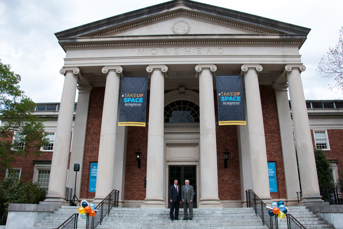 Morehead's director, Todd Boyette and Apollo 13 commander, James Lovell, stand under banners on Morehead's west entrance.