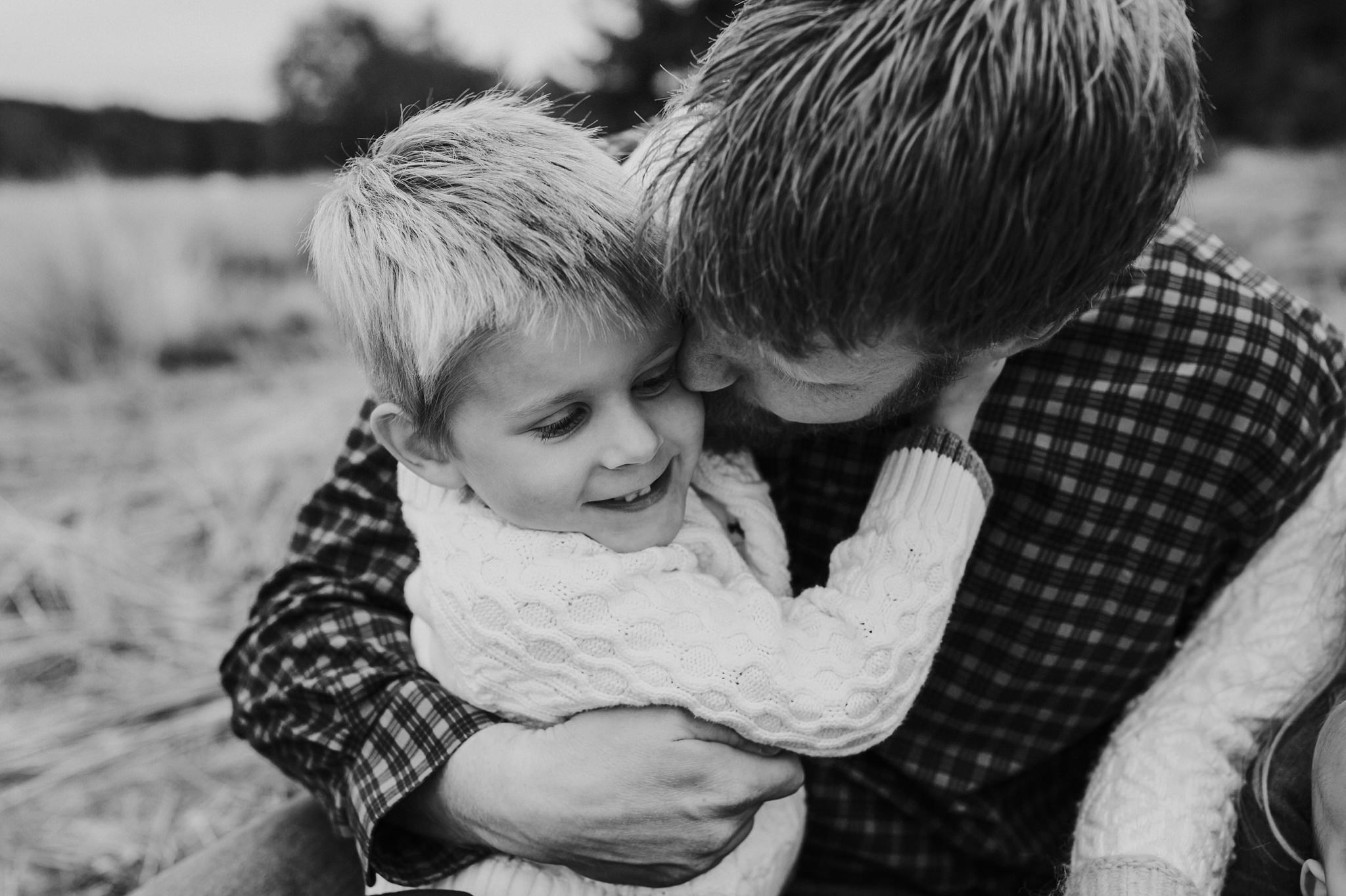 kara chappell whidbey island family photography dad snuggles son on blanket at park