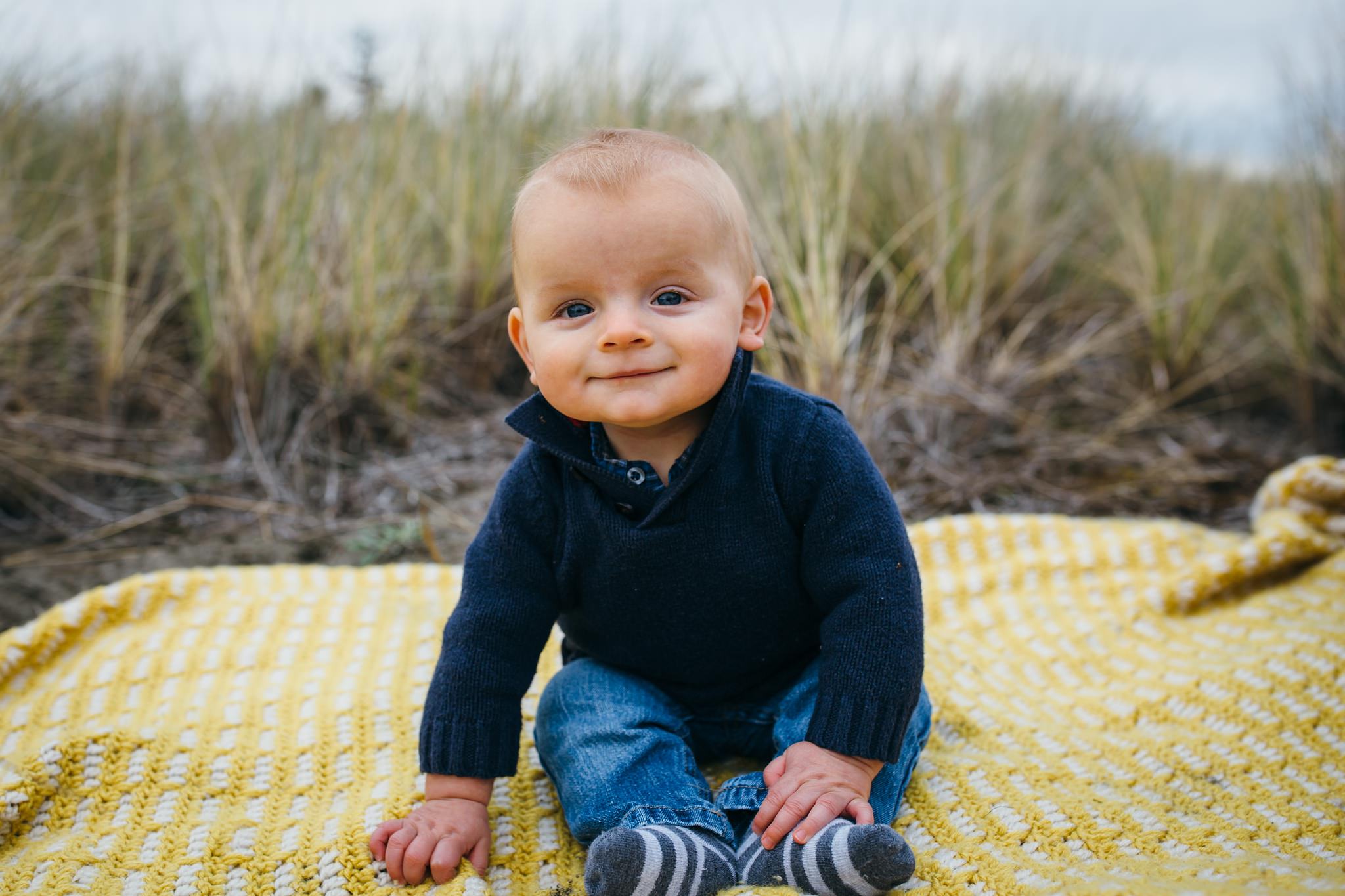 kara chappell whidbey island family photography baby boy sits on yellow blanket at beach