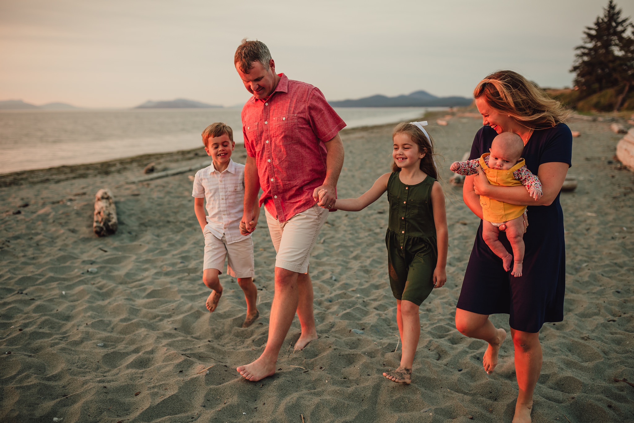 family walks down Whidbey Island beach during portrait session