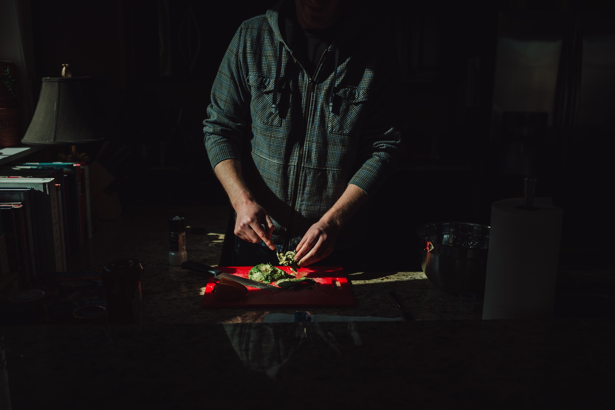 man cuts vegetables in kitchen while standing in harsh light | Whidbey Island family photographer