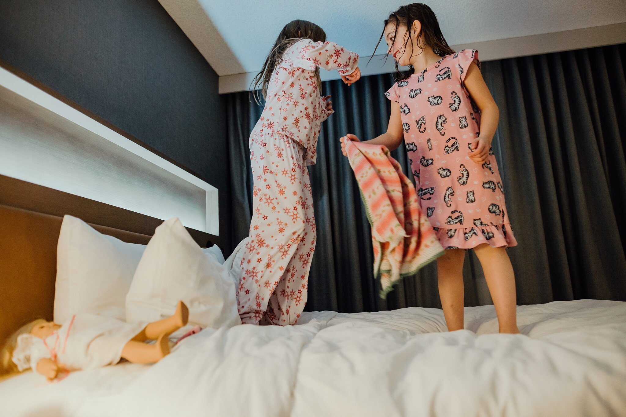 girls jump on bed in hotel