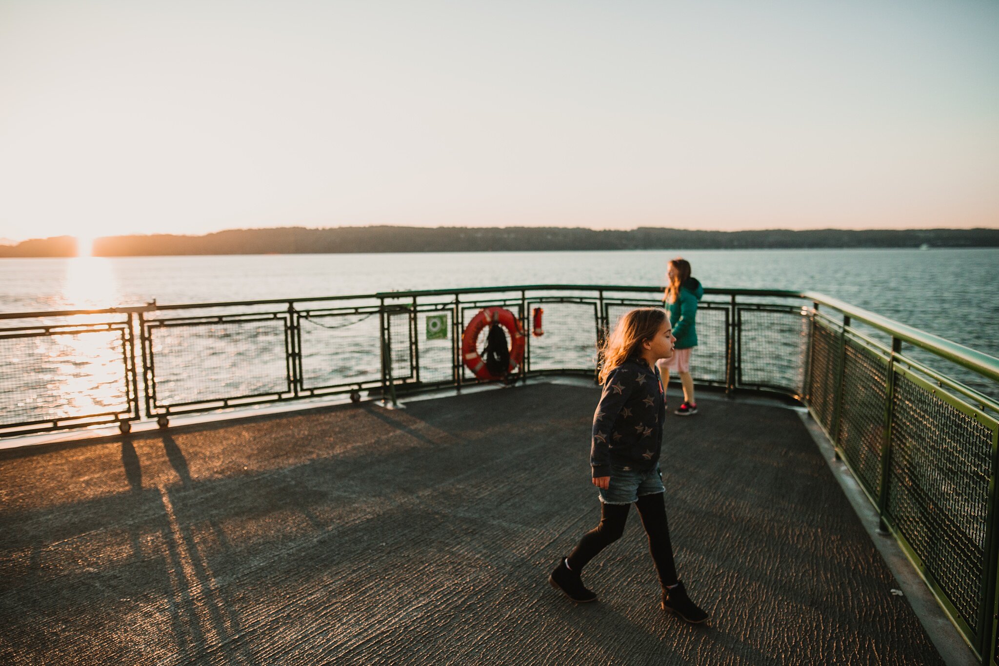girls walk across ferry at sunset