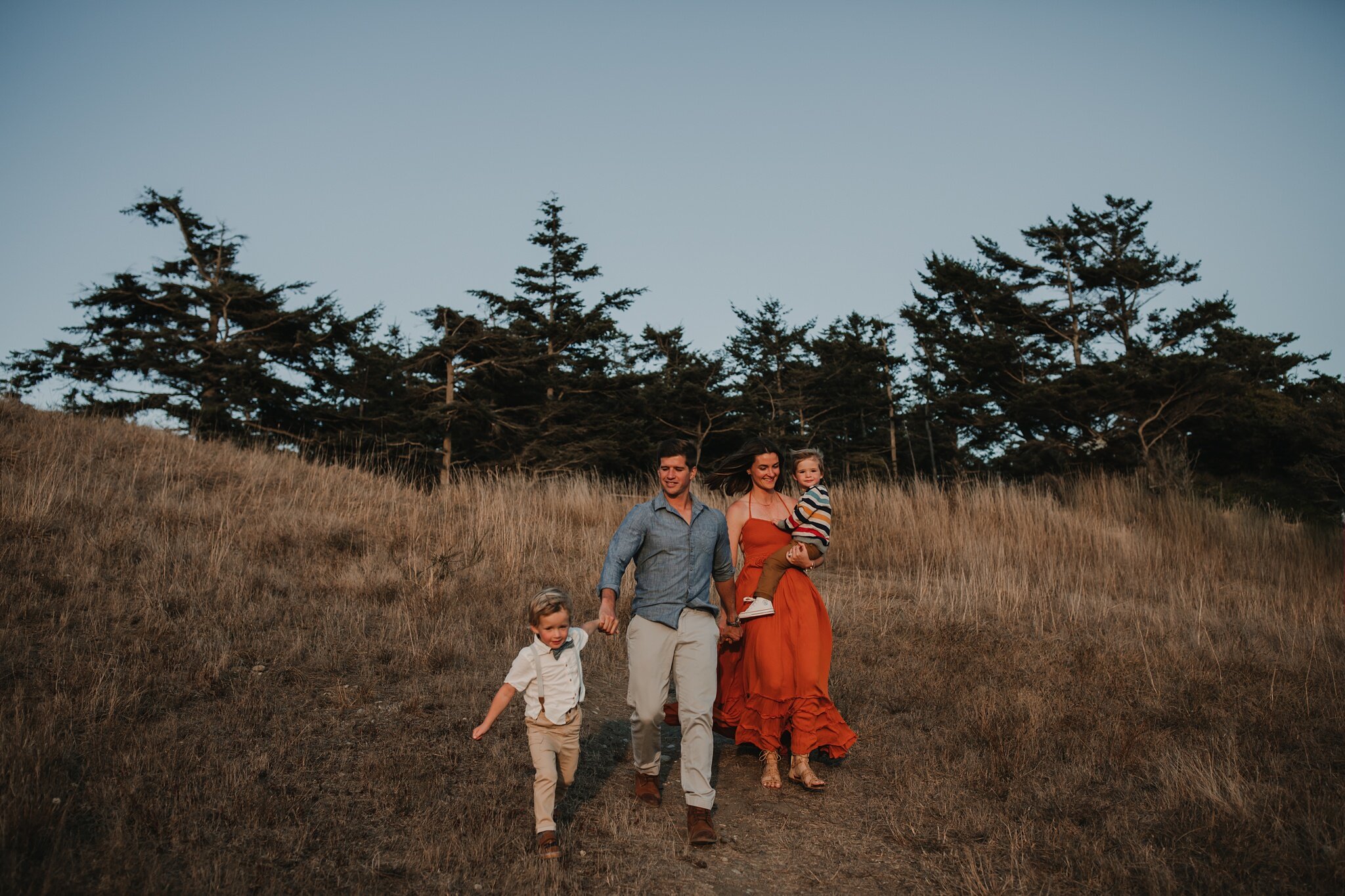 family runs down hill on whidbey island during family photoshoot