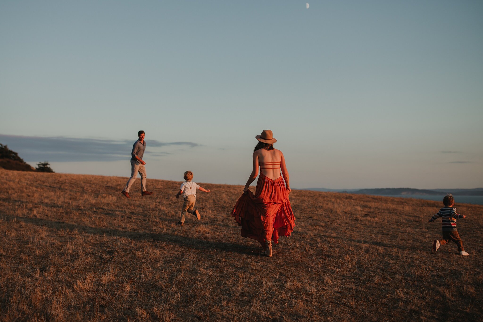 family walks up hill at sunset
