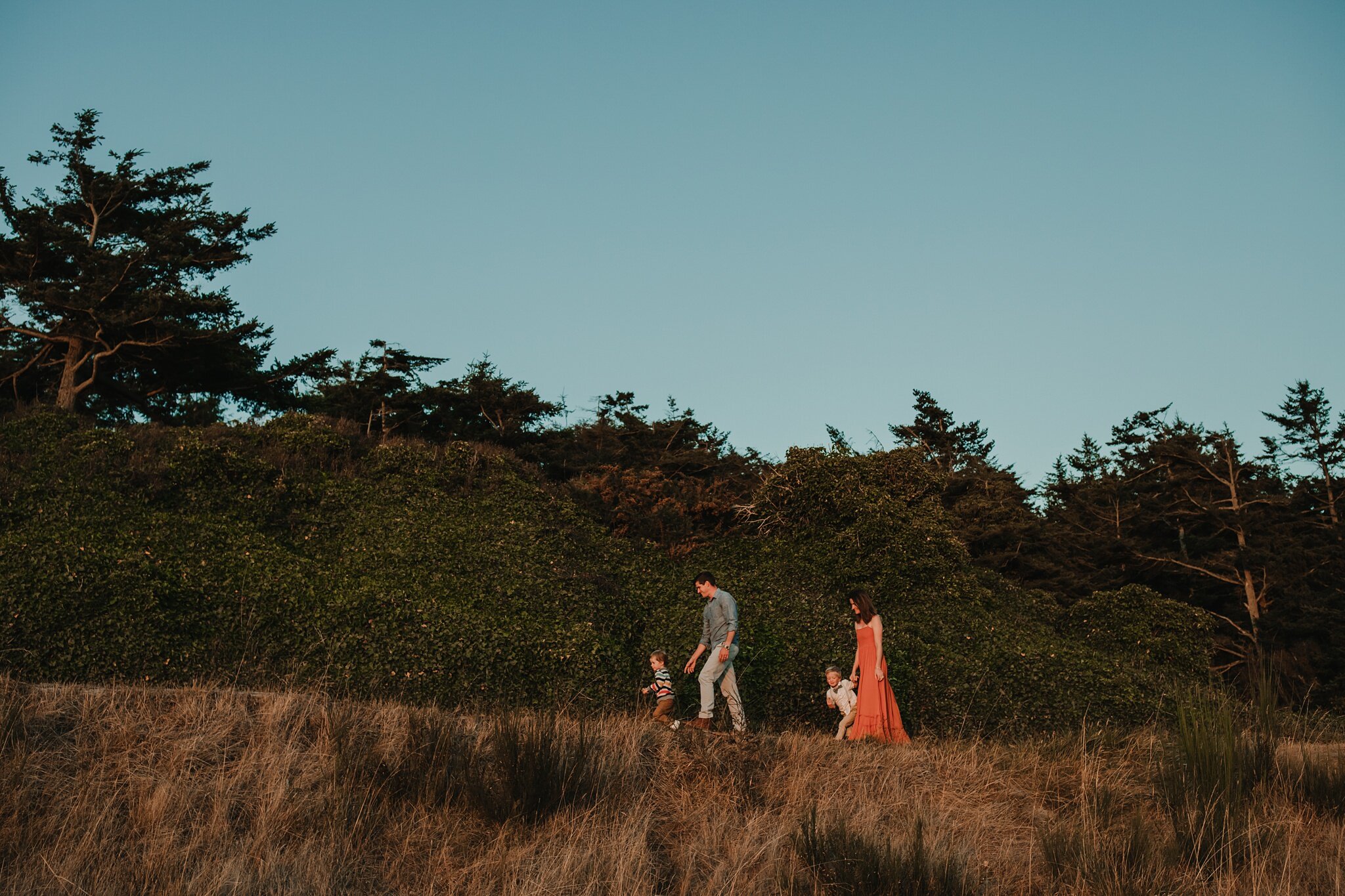 beautiful family walks up tree-adorned hill at fort ebey