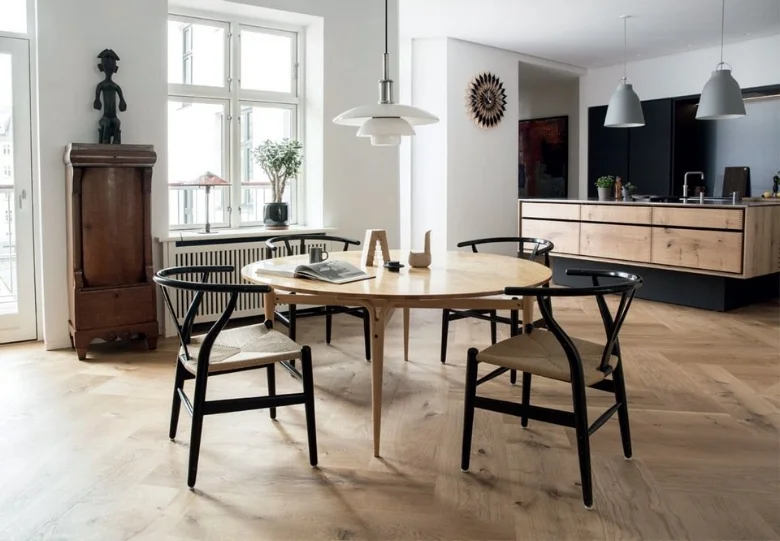 The dining room is decorated with bright, simplistic design and black Wishbone chairs from Hans Wegner gives edge to an inherited Bruno Mathsson table. Poul Henningsen pendant lamp with opal glass shade provides a soft light over the table during meals.