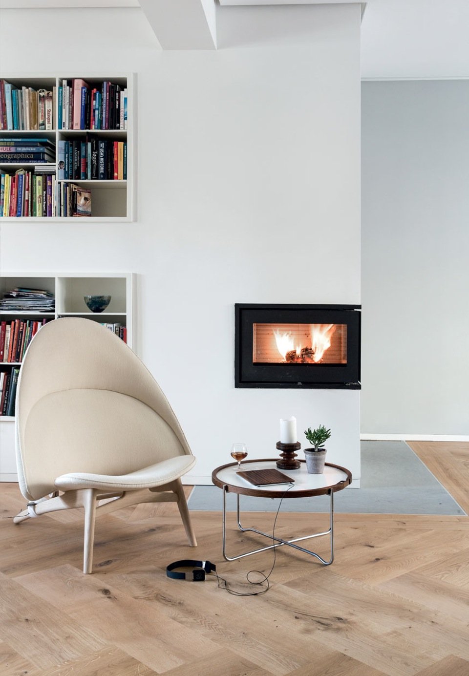 Modern and timeless nook with built-in shelving and Rais fireplace. The chair is the PP 530 Tub Chair by Hans Wegner recently put into production. The domed lines are repeated in the table, also by Hans Wegner, where the wooden frame creates a soft contrast to the metal legs. By mixing woods creates Søren life and warmth in the interior.