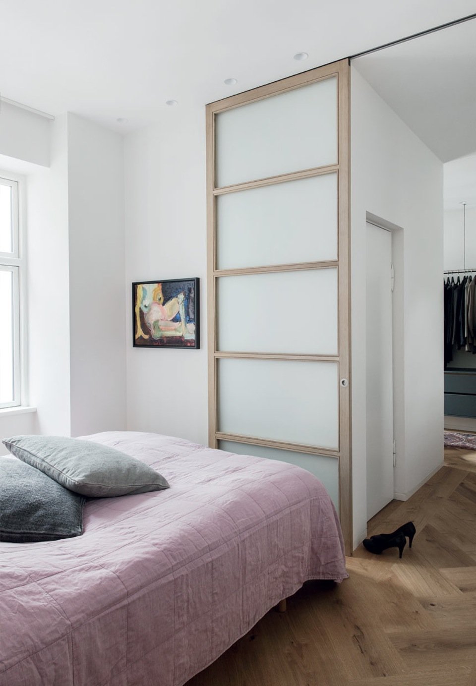 A sliding door in light ash wood glides over herringbone parquet floor, and with the absence of a doorstep lends to a minimalist Japanese feeling to lift the boundaries between rooms.