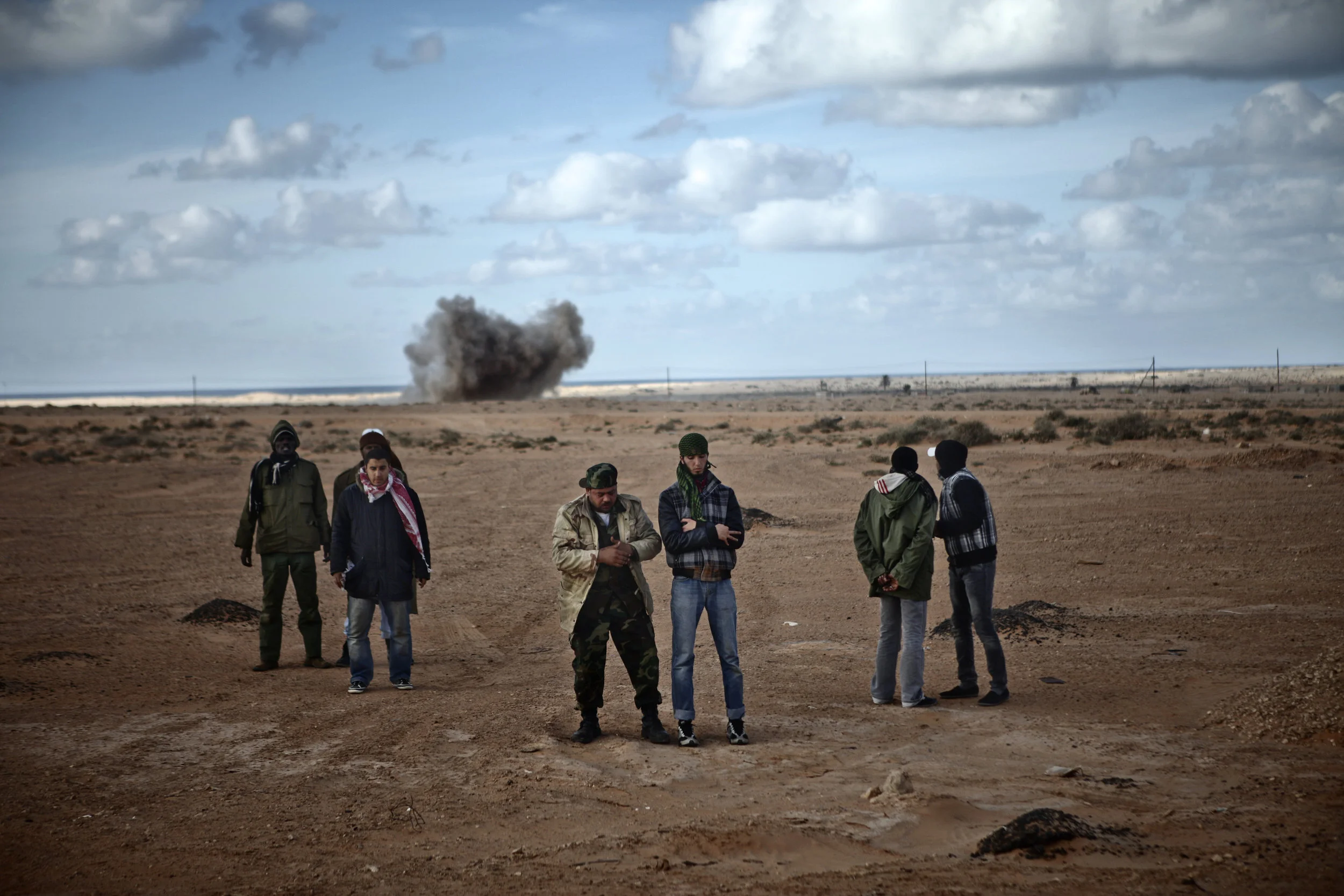  3/6/2011 Bin Jawad, Libya  Anti-Qaddafi rebels made their evening prayers as artillery rounds fired by Pro-Qaddafi forces explode nearby in the background, near Bin Jawad.  