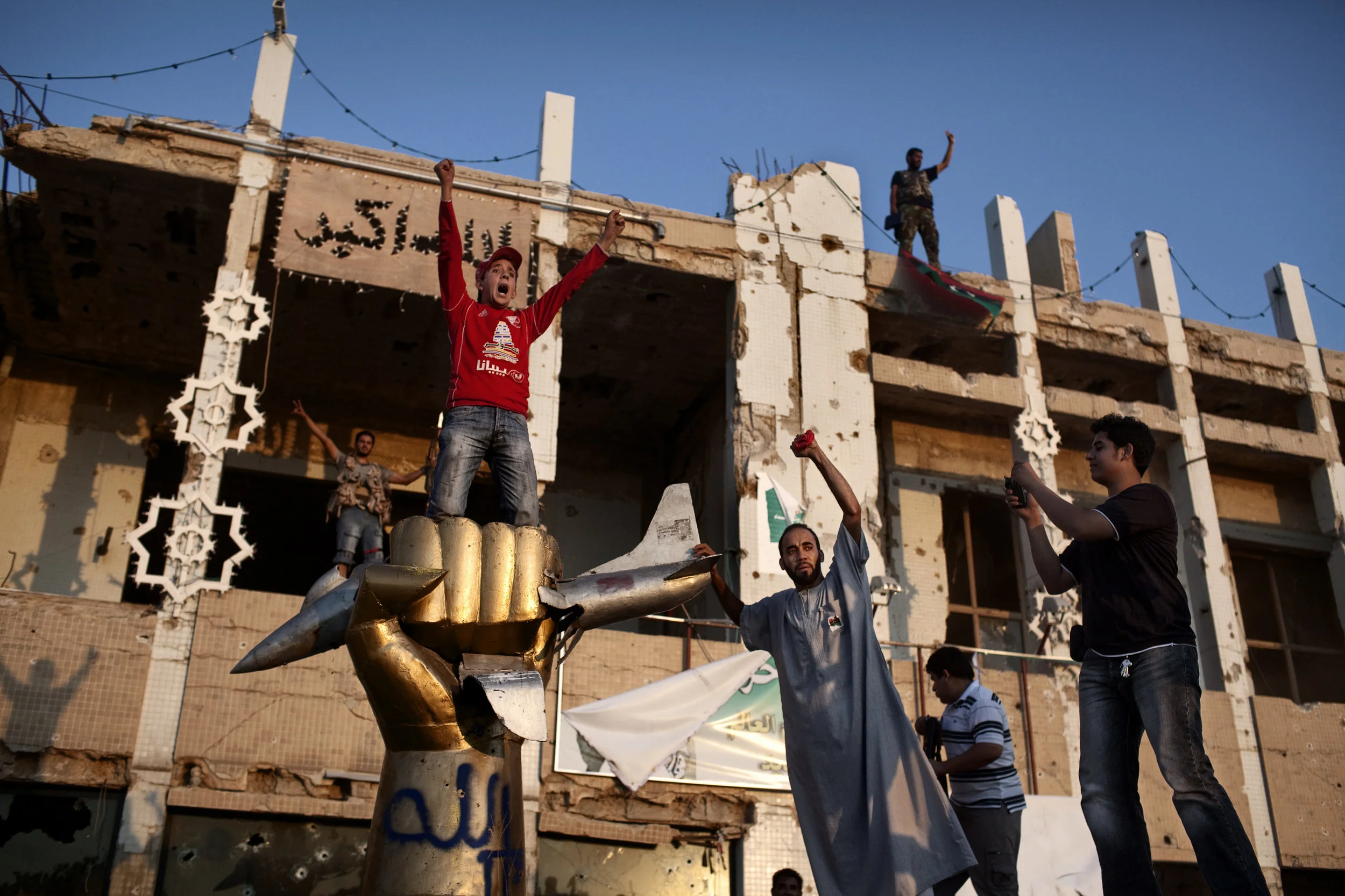  8/23/2011, Tripoli, Libya  Rebels celebrated on top of a statue of a fist crushing an Ameircan plane—a well known landmark on Qaddafi’s Bab al-Azizia compound. 