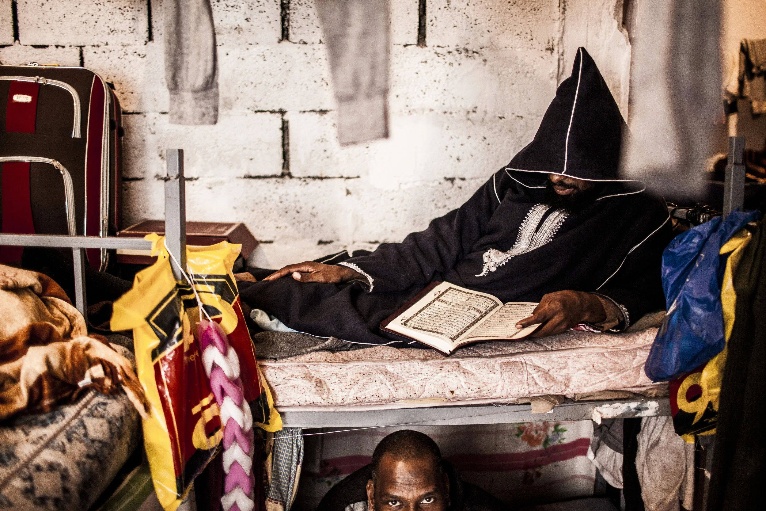  1/28/2012 Misurata, Libya  A man from Tawaraga, currently imprisoned at a prison in Misurata's former internal security building reads the koran on his cot in a large open cellblock. The prisoners were under the care of a Salafi Sheikh and his follo