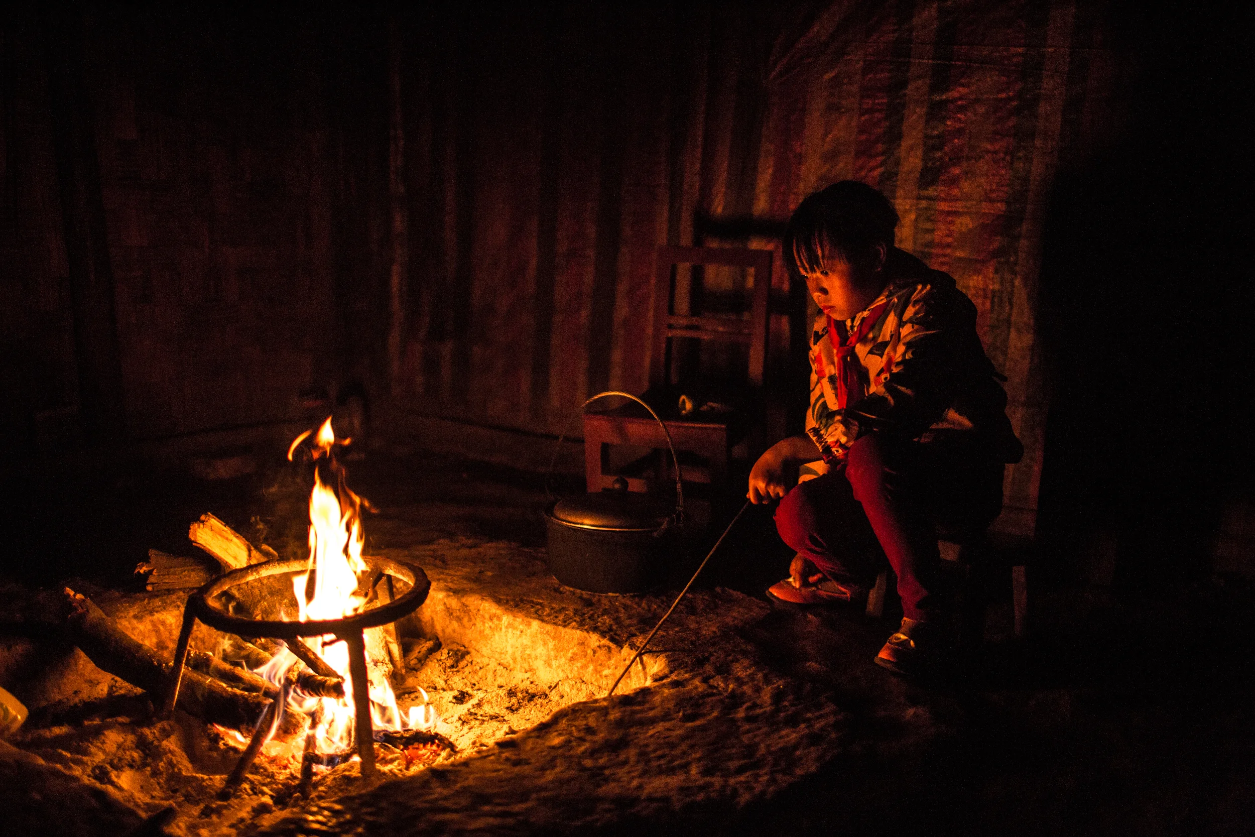 4/13/2018 Zhongdong, Guizhou Province, China. A young resident of the Zhong cave, back from a week at boarding school, sat with her mother as she prepared dinner at their home in the cavern. Children as young as 5 now spend most of the week away from home at school, a common practice in China's rural communities.