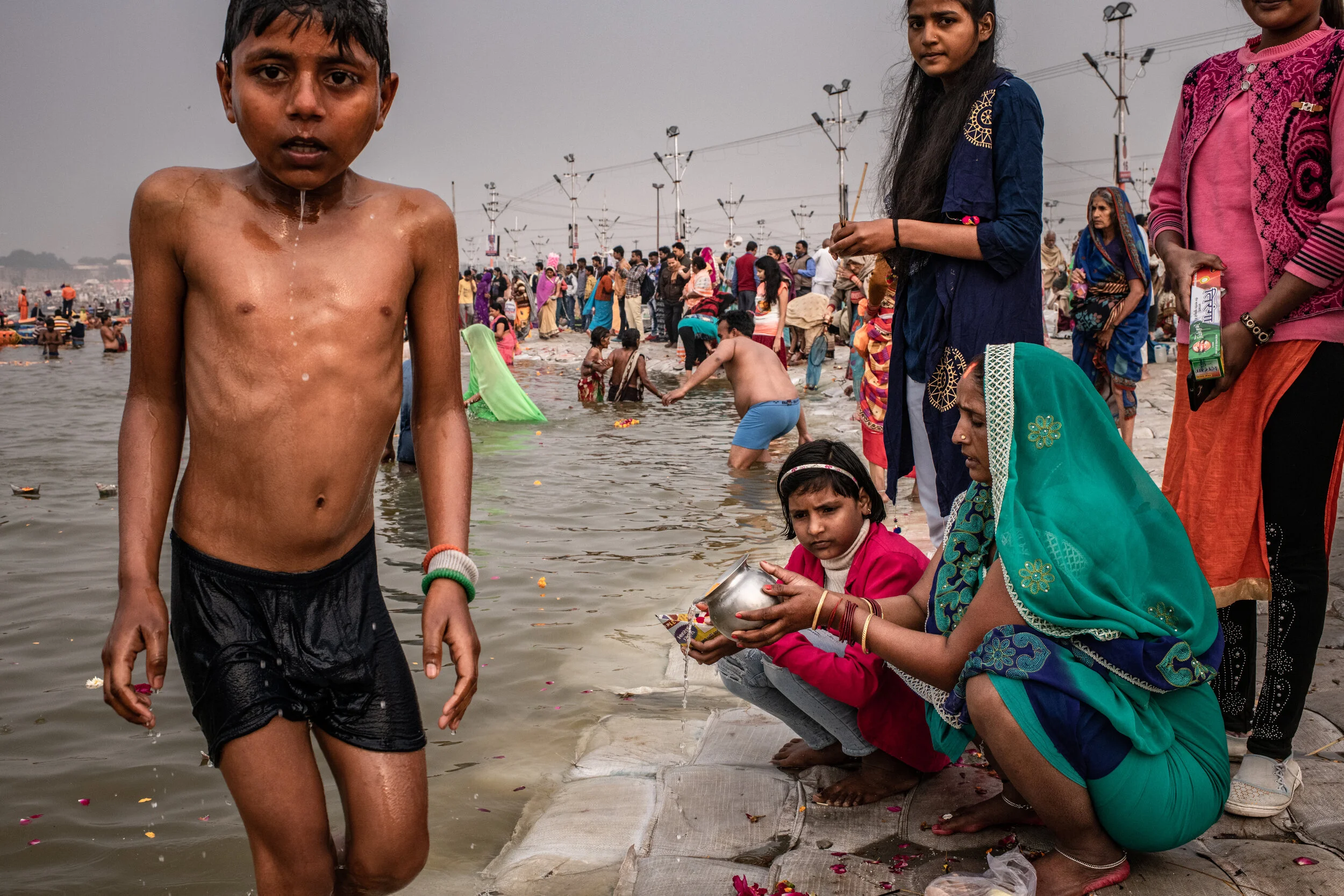  2/7/2019 Prayagraj, Uttar Pradesh, India  A young pilgrim shivered after emerging from the waters of the holy Sangam bathing area at the confluence of the Ganges and Yamuna rivers, in Prayagraj, India, as women made offerings nearby, during the Ardh