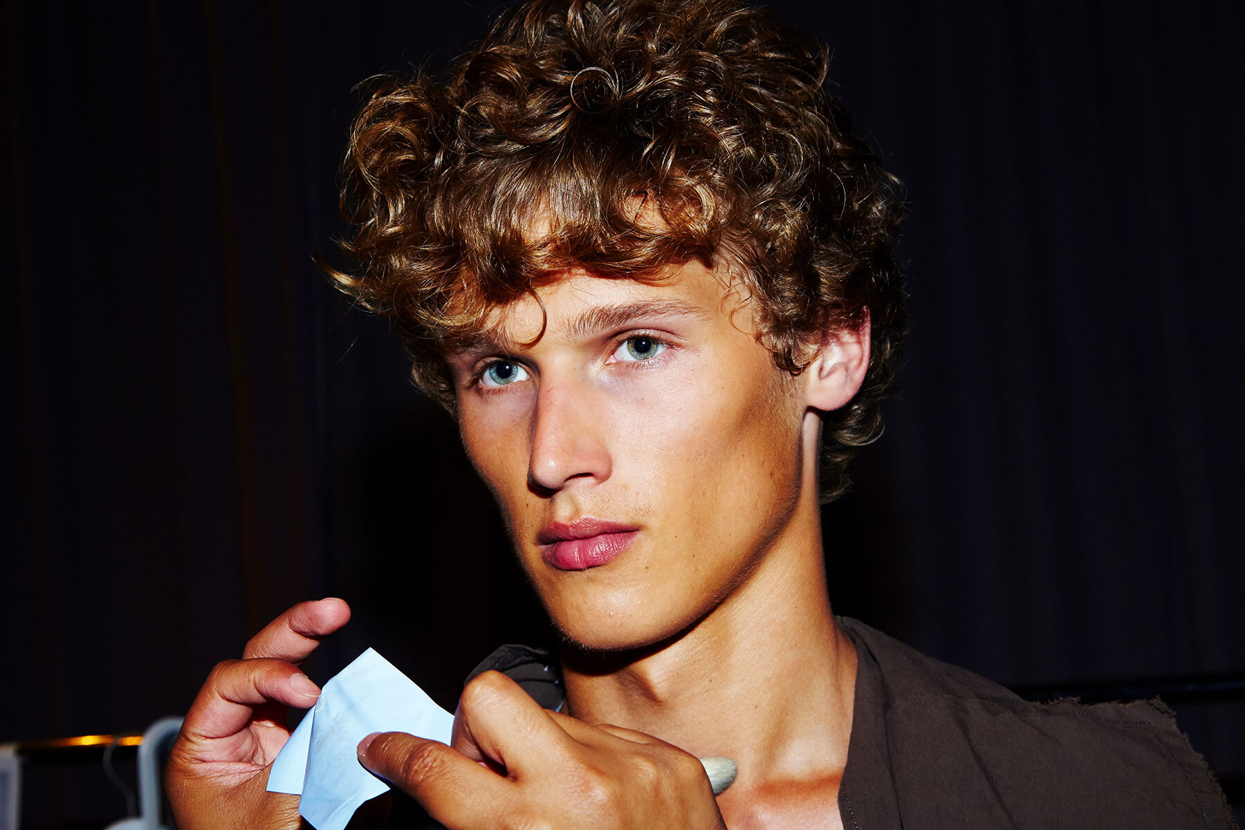 A male model has his makeup retouched backstage at Robert Geller for Spring/Summer 2017.