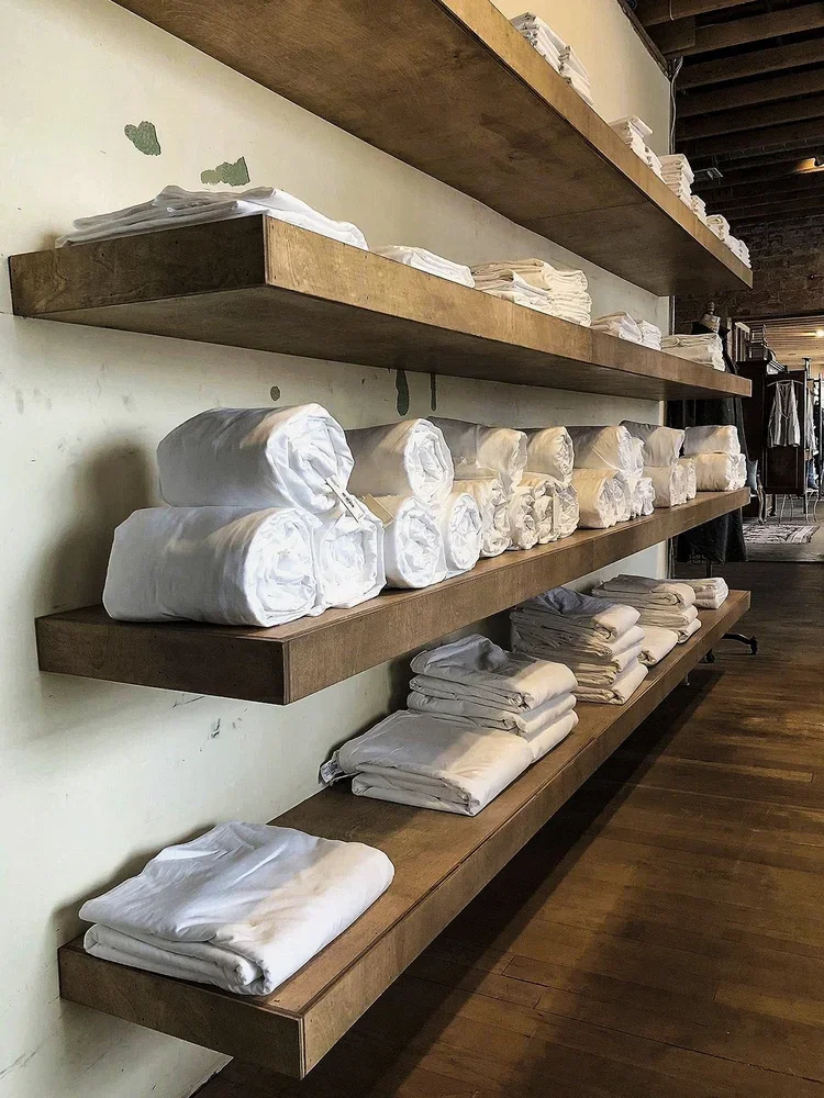 Shelves with stacks of folded and rolled white linens or clothing in a store or warehouse.