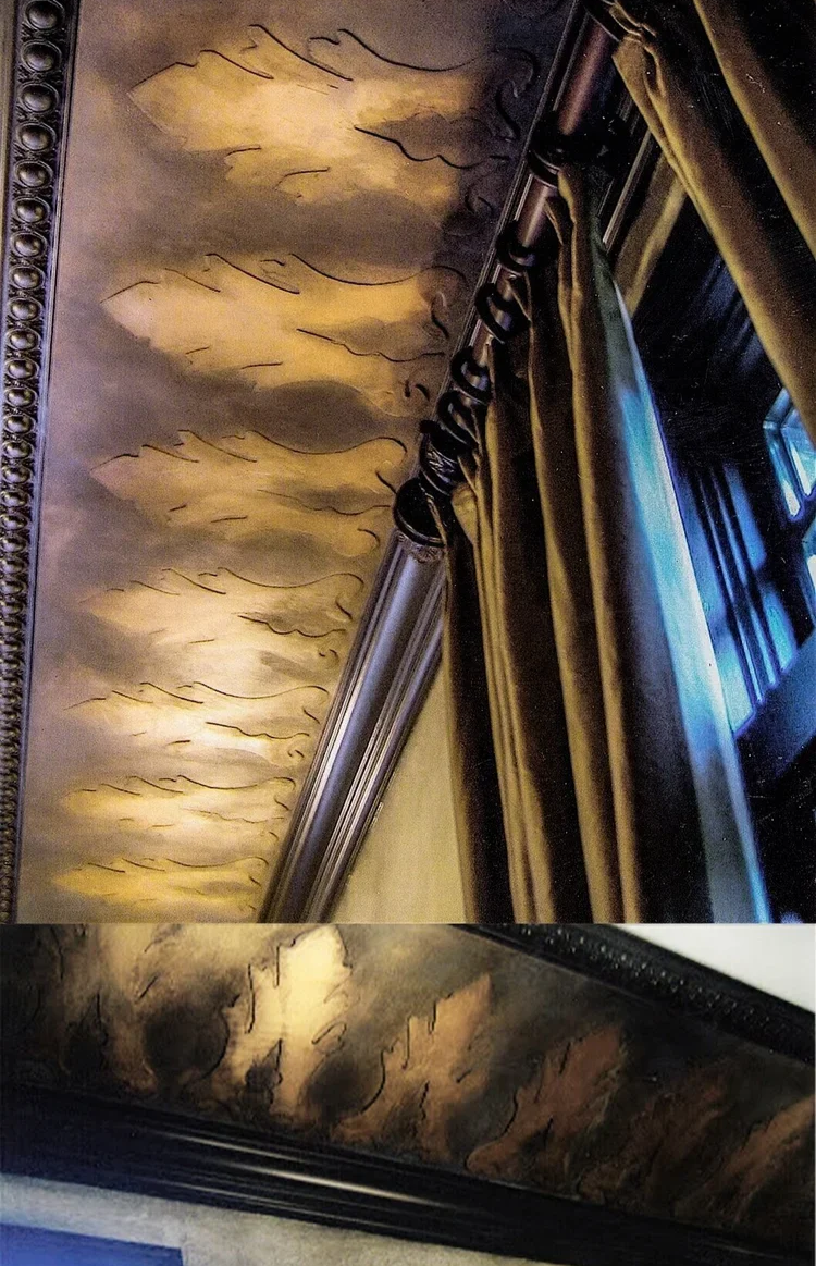 Close-up of ornate ceiling with gold painted clouds and decorative crown molding, part of a luxurious interior. Also shows a window with curtains.