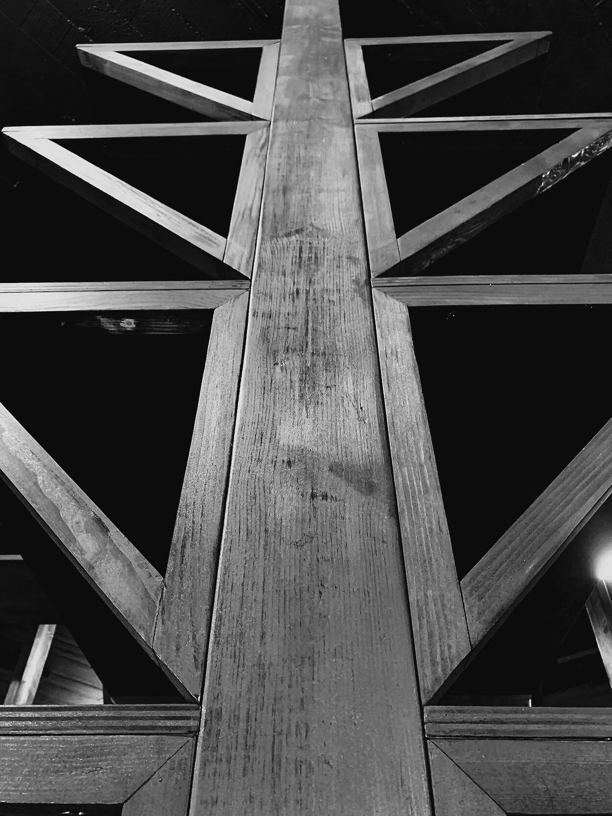 Black and white image of a wooden cross with triangular supporting beams.