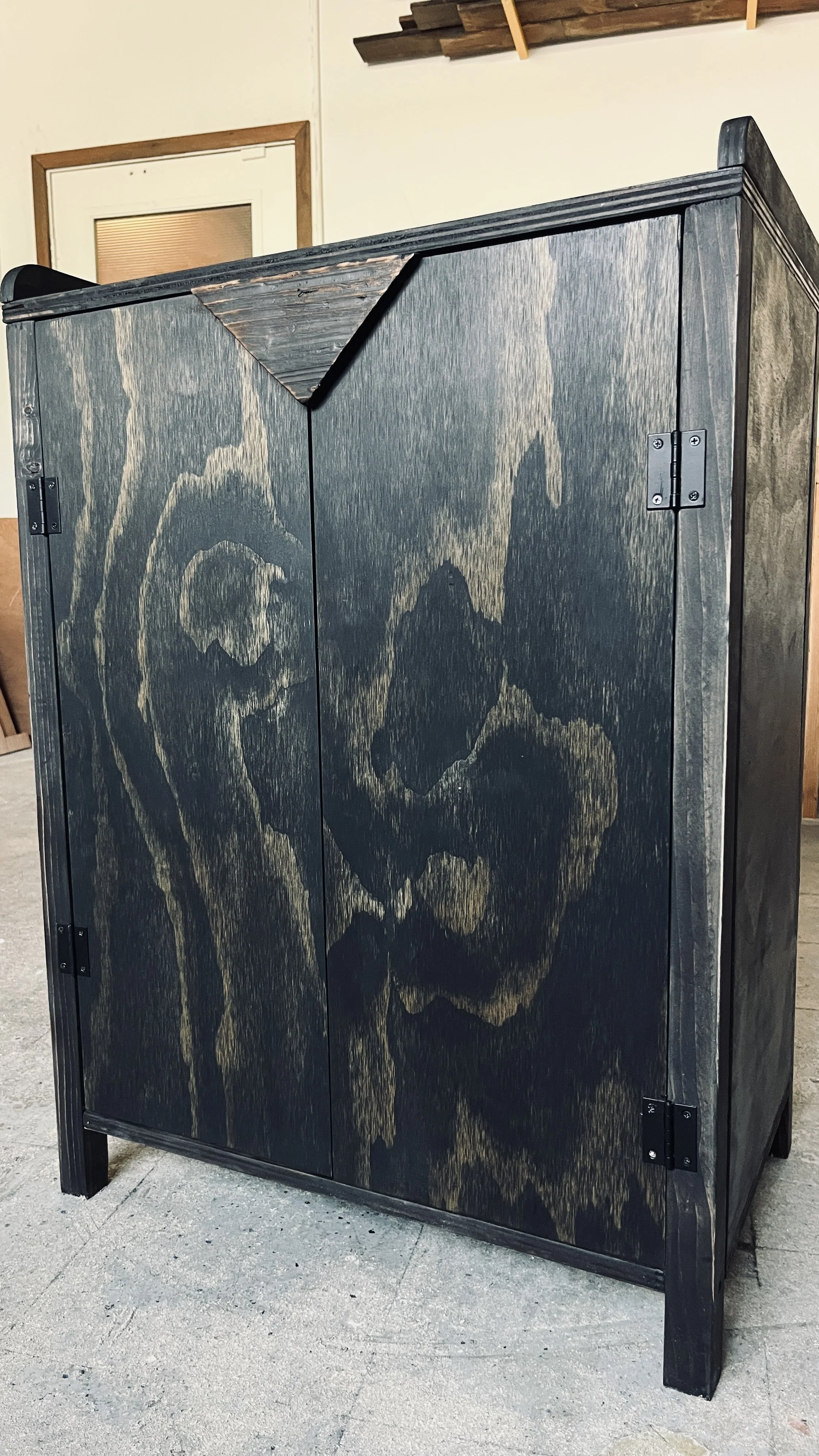 A black wooden cabinet with skull and crossbones designs painted on its doors.