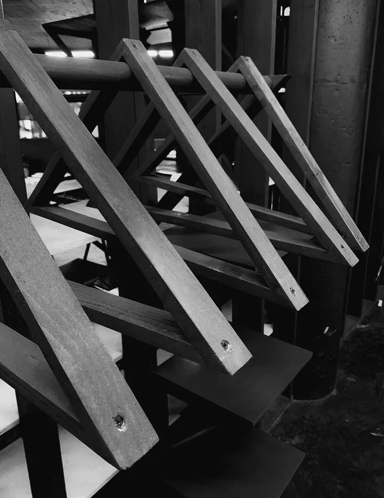 Stacked wooden chairs upside down on black tables in a dimly lit indoor space.