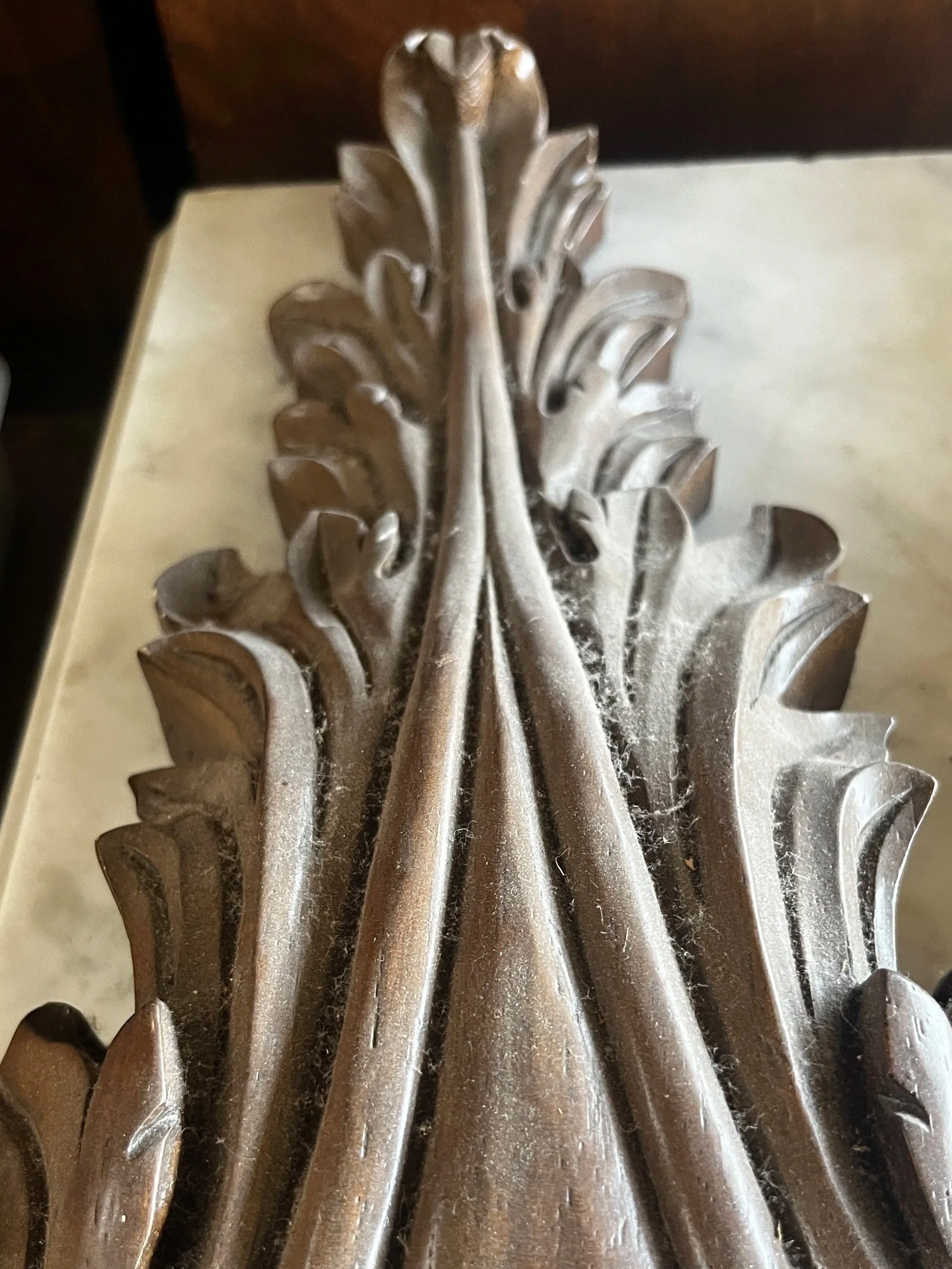 Close-up of an ornate, carved wooden furniture piece with intricate leaf and vine patterns.