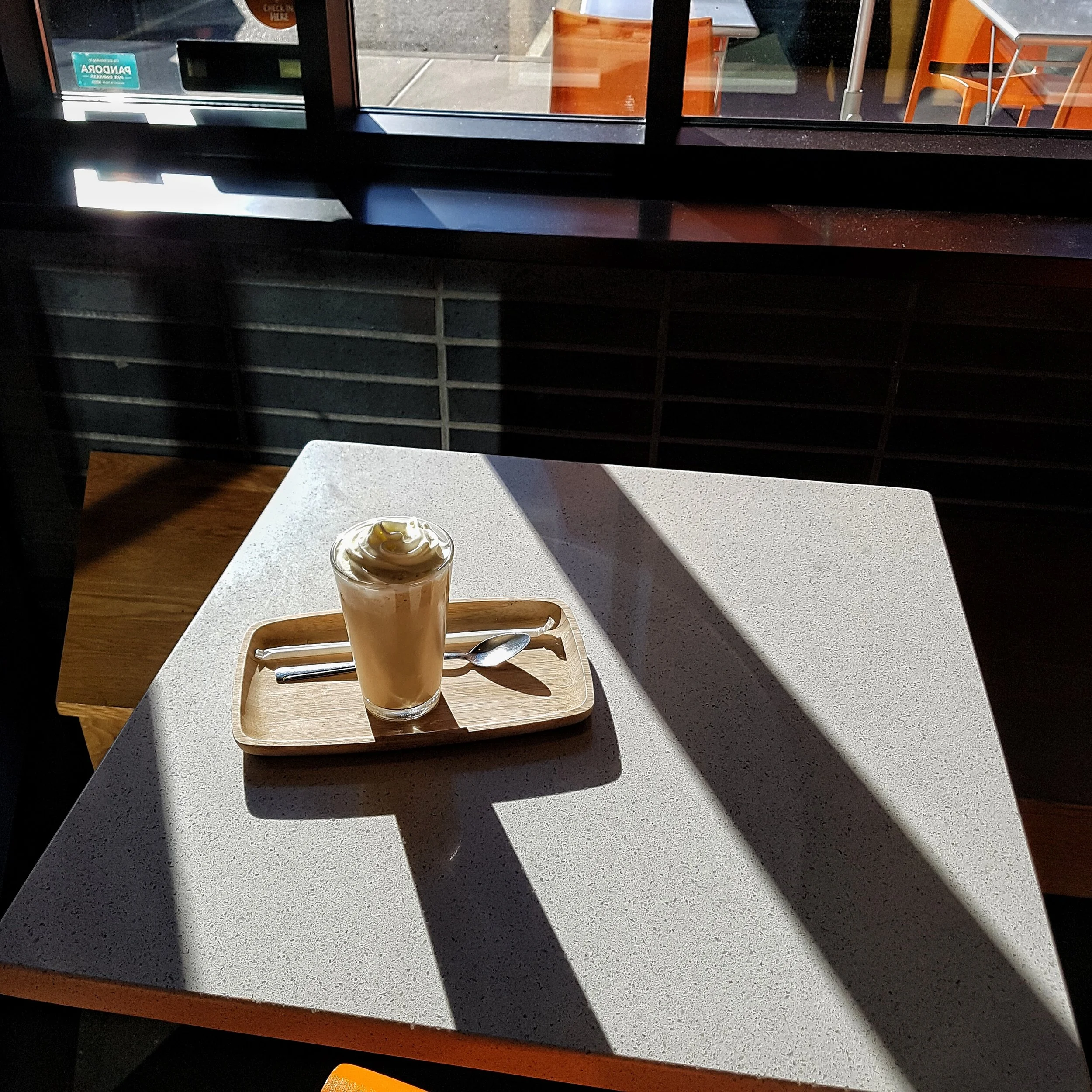 A milkshake sits on a table in the sun