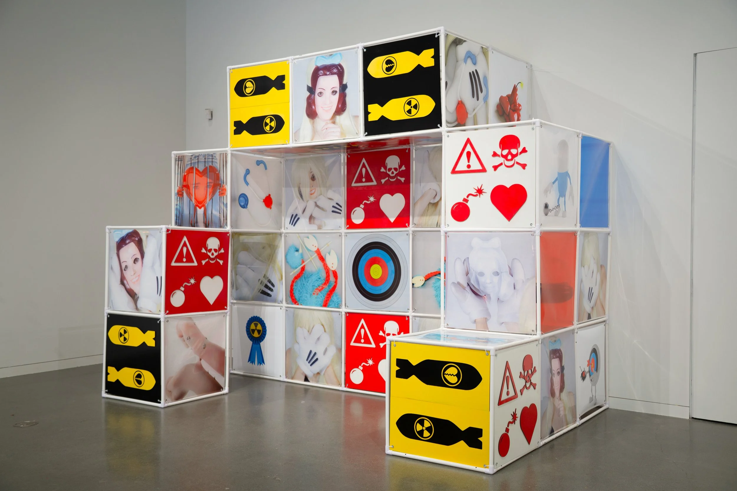 An Attraction (2025) Installation with polyvinyl chloride pipe, inkjet prints on celluloid film, maple plywood coated in federal standard Occupational Safety and Health Administration (OSHA) enamel paint and polyurethane high gloss, silver gromme