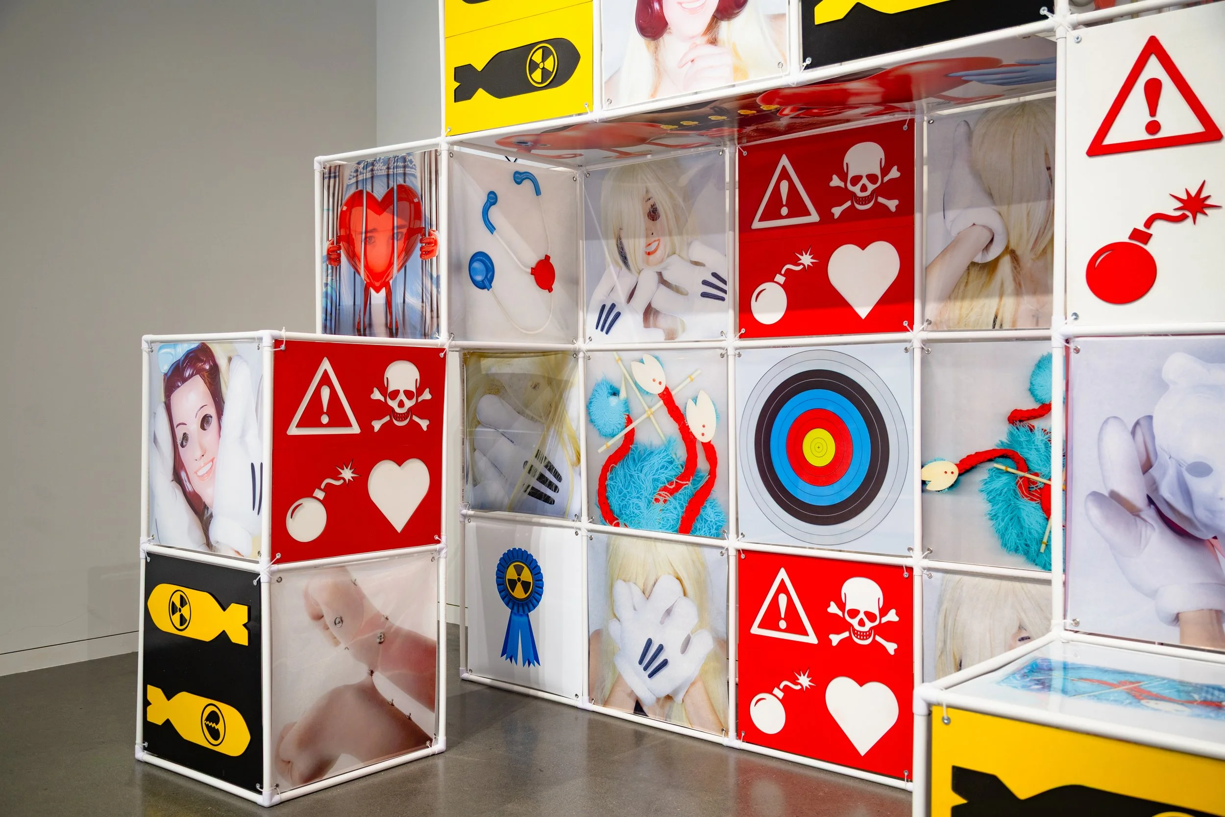An Attraction (2025) Installation with polyvinyl chloride pipe, inkjet prints on celluloid film, maple plywood coated in federal standard Occupational Safety and Health Administration (OSHA) enamel paint and polyurethane high gloss, silver gromme