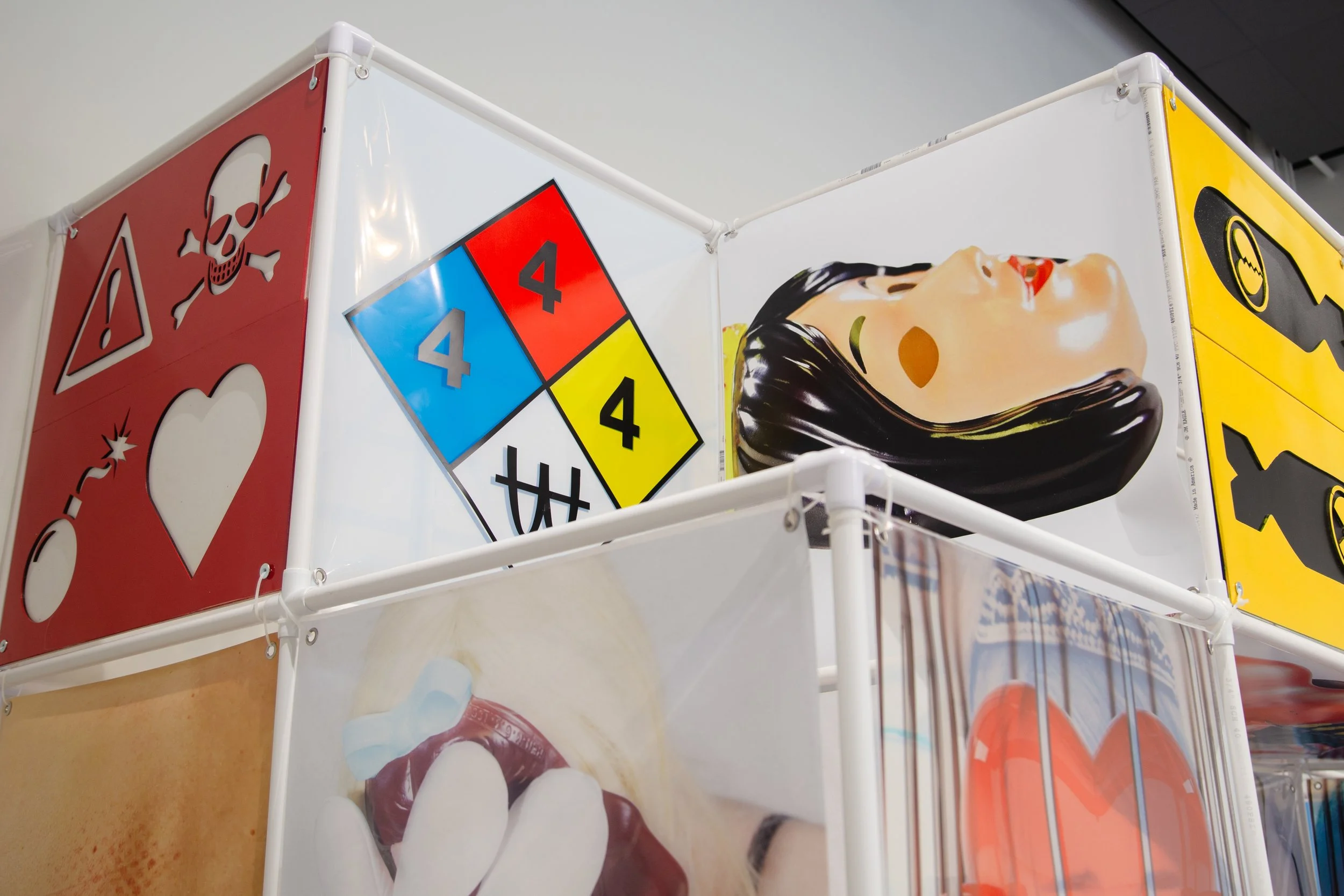 An Attraction (2025) Installation with polyvinyl chloride pipe, inkjet prints on celluloid film, maple plywood coated in federal standard Occupational Safety and Health Administration (OSHA) enamel paint and polyurethane high gloss, silver gromme