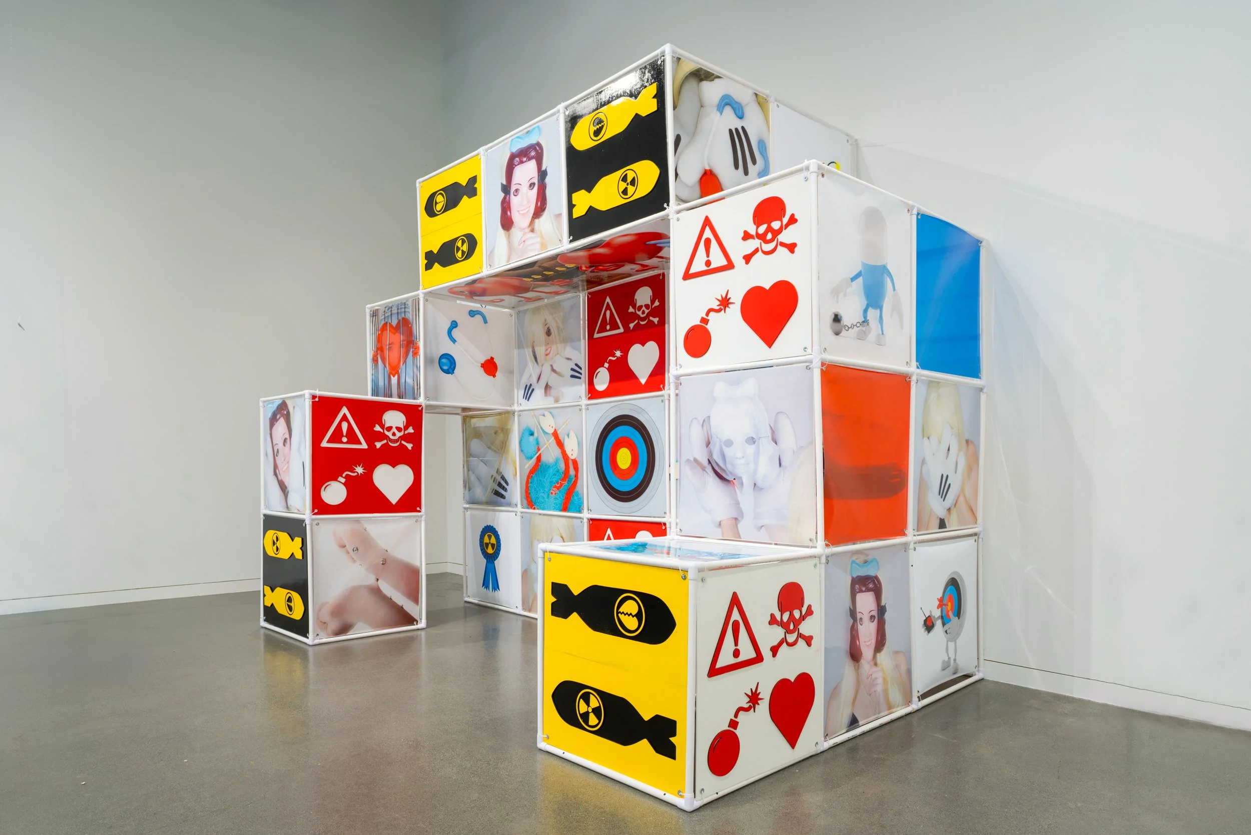 An Attraction (2025) Installation with polyvinyl chloride pipe, inkjet prints on celluloid film, maple plywood coated in federal standard Occupational Safety and Health Administration (OSHA) enamel paint and polyurethane high gloss, silver gromme