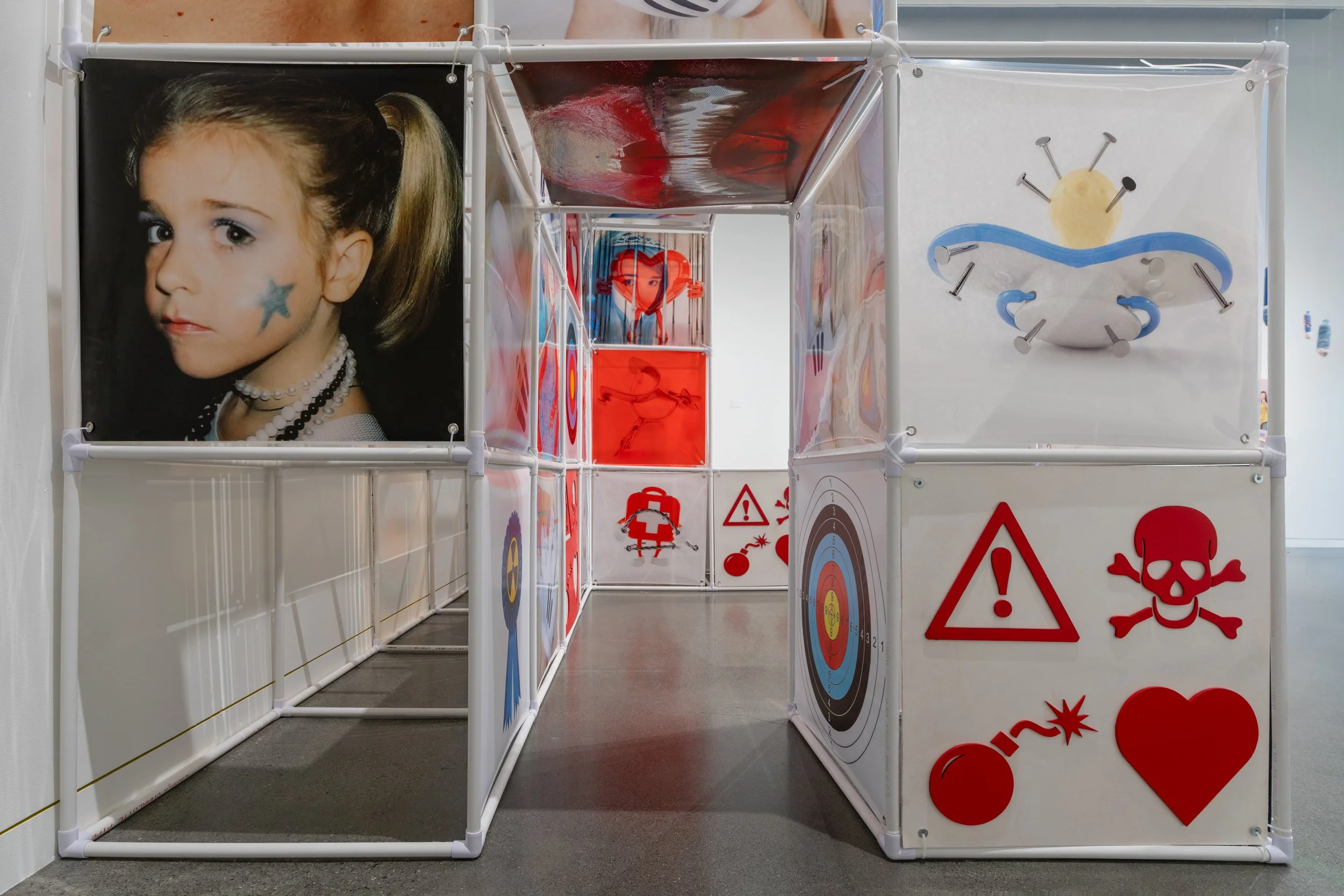 An Attraction (2025) Installation with polyvinyl chloride pipe, inkjet prints on celluloid film, maple plywood coated in federal standard Occupational Safety and Health Administration (OSHA) enamel paint and polyurethane high gloss, silver gromme