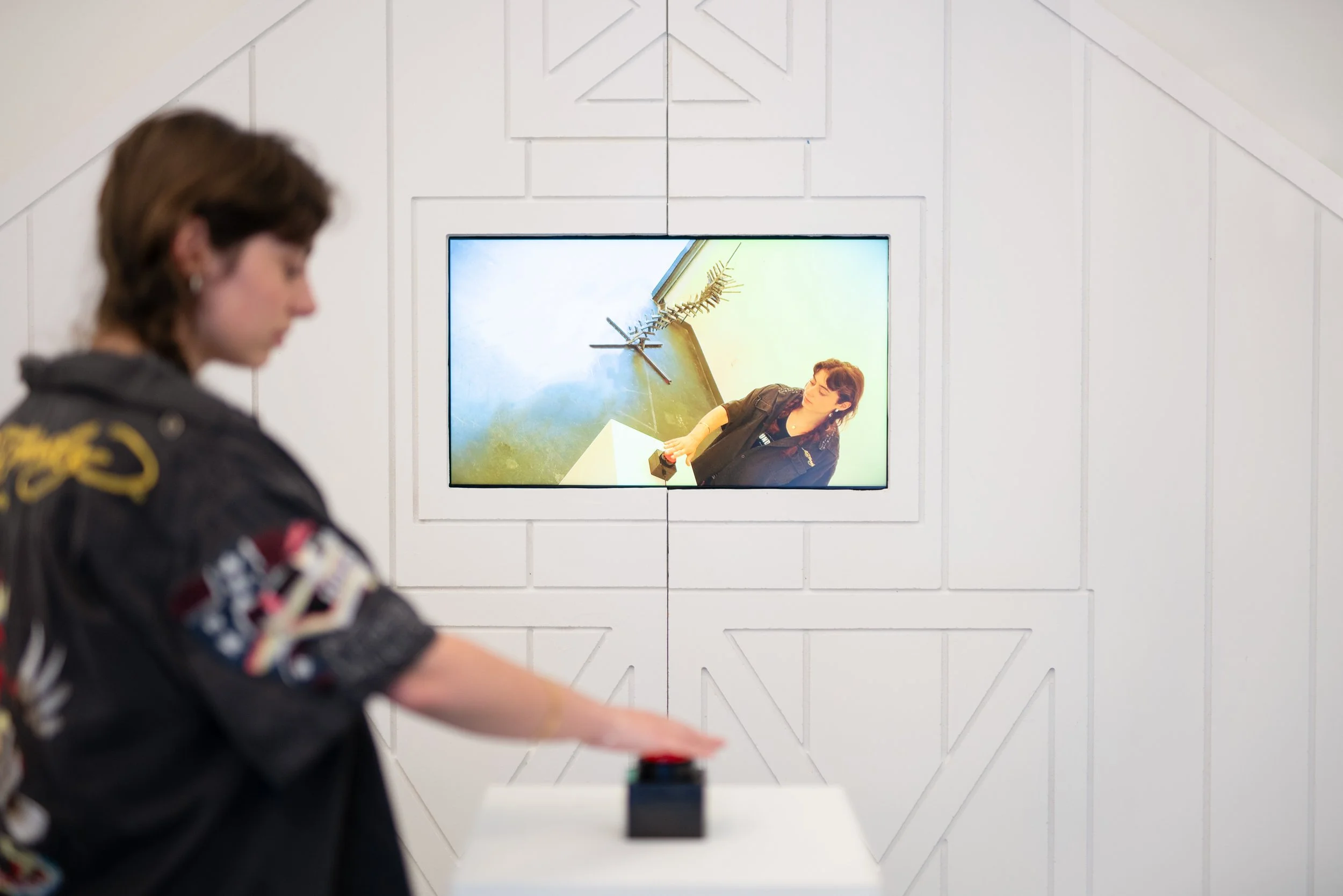 Running Scared Set Piece (2025) Multimedia installation with melamine white particle board, polyurethane gloss, plywood, monitor, button, pedestal 11ftx7ft