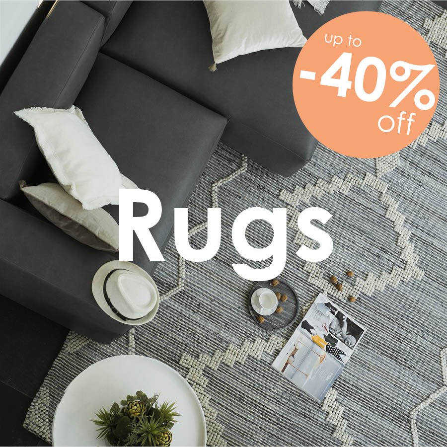 Overhead view of a textured grey and cream geometric area rug beneath a modern charcoal sectional sofa