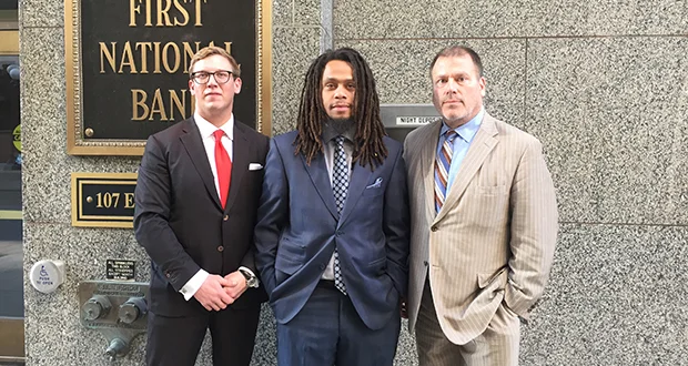 Christopher Lollie (center) stands with attorneys Andrew Irlbeck (left) and Paul Applebaum at the the First National Bank Building in St. Paul. A lawsuit over Lollie's arrest in the skyway of that building cost the city of St. Paul $100,000. 