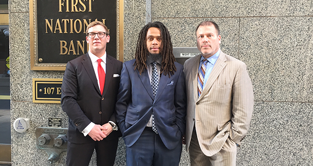 Christopher Lollie (center) stands with attorneys Andrew Irlbeck (left) and Paul Applebaum at the the First National Bank Building in St. Paul. A lawsuit over Lollie's arrest in the skyway of that building cost the city of St. Paul $100,000. 