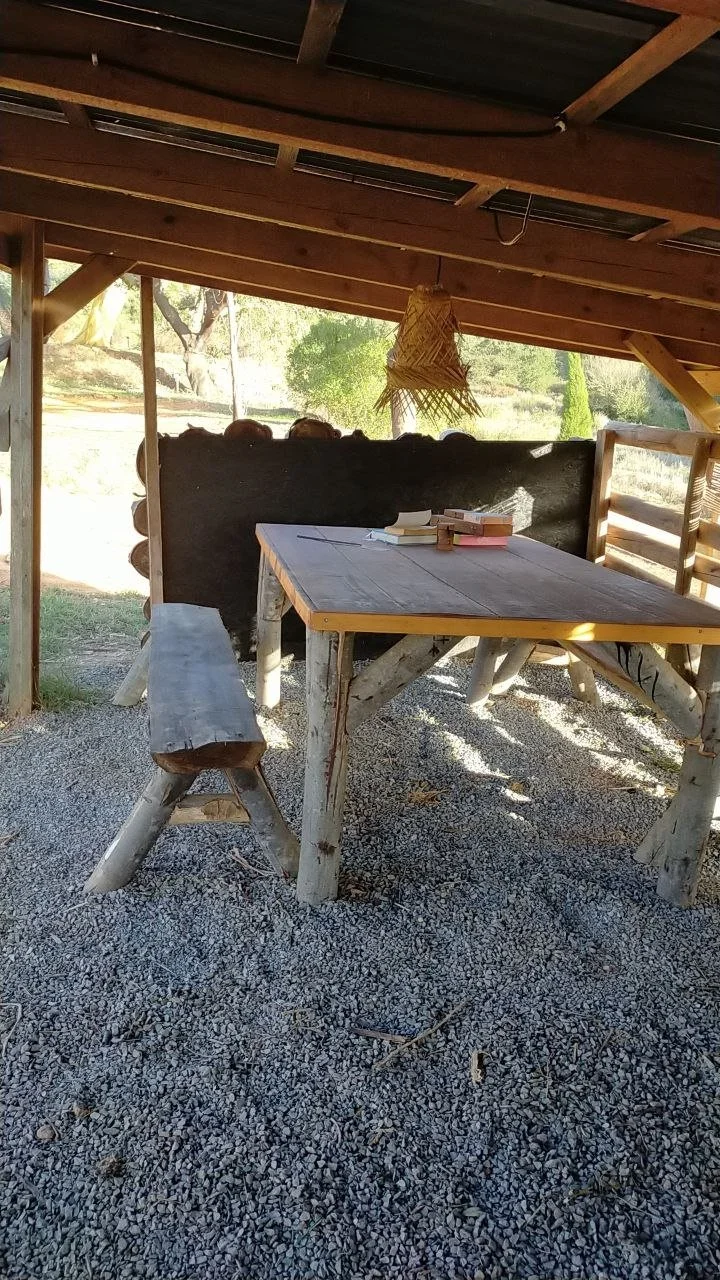 A heavy wooden dining table and matching bench in the outdoor kitchen area, perfect for communal meals.