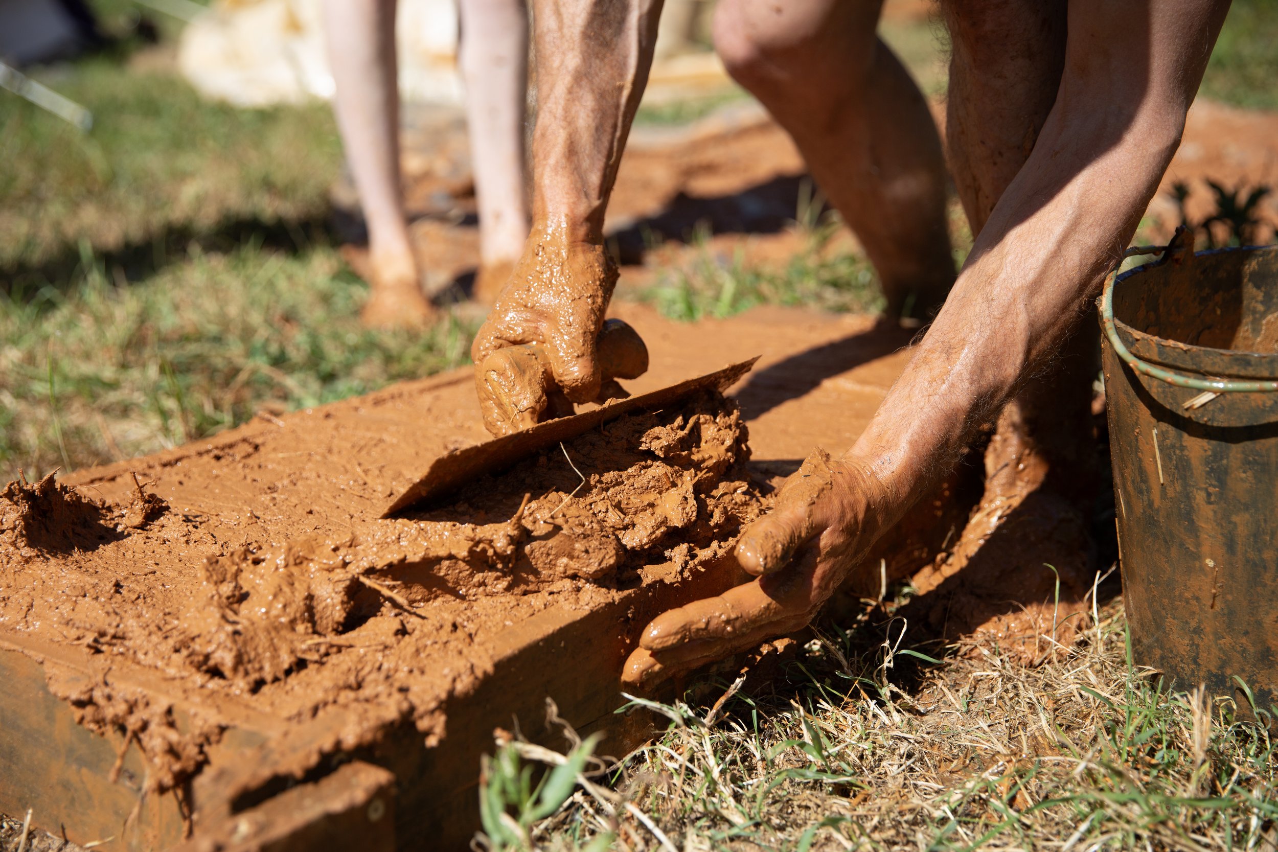 Muddy hands making an adobe brick during natural building course with Lola Byron at A Quinta, Alentejo, Portugal